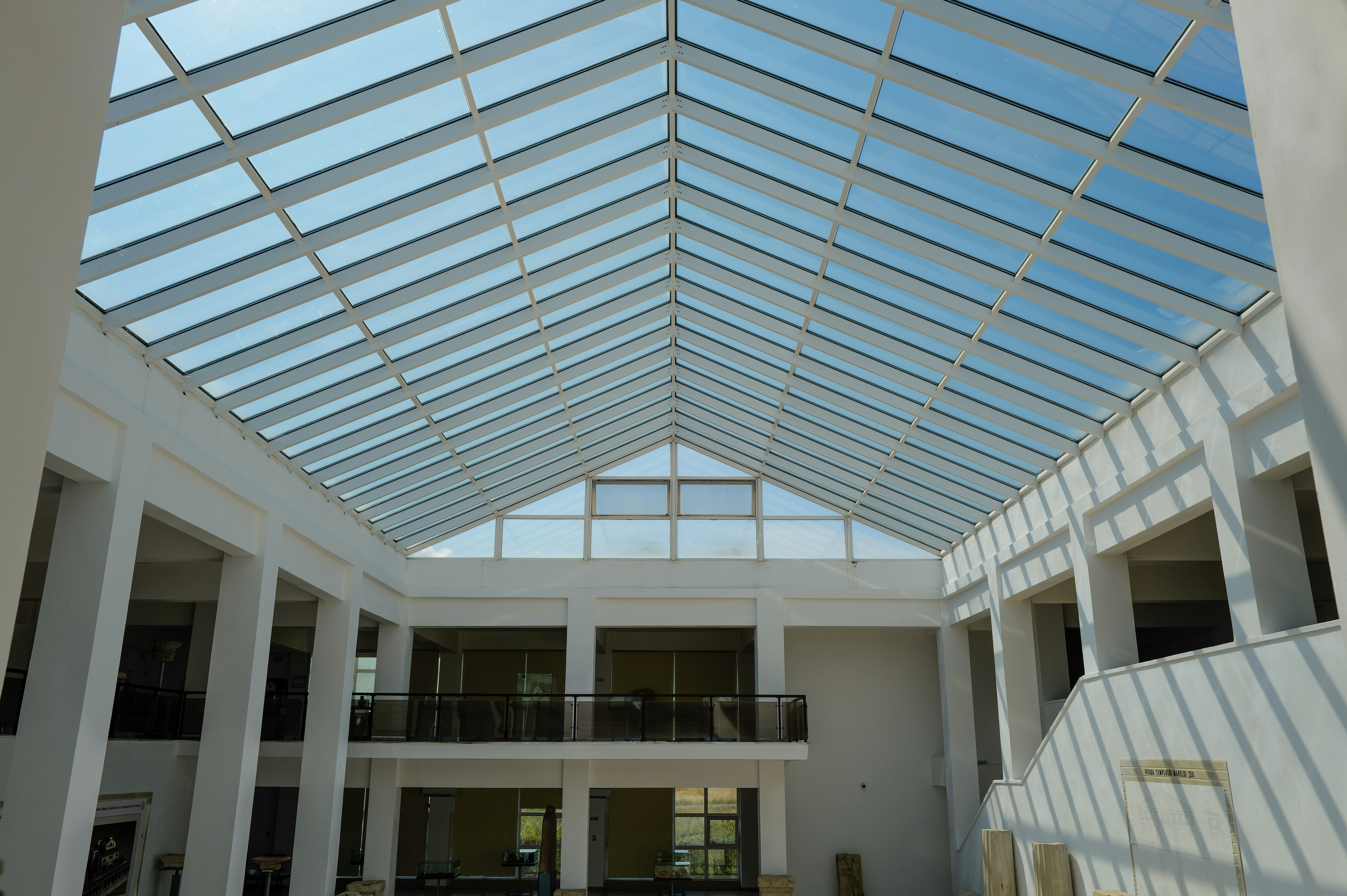 Bright atrium interior with a large glass gabled roof and white columns