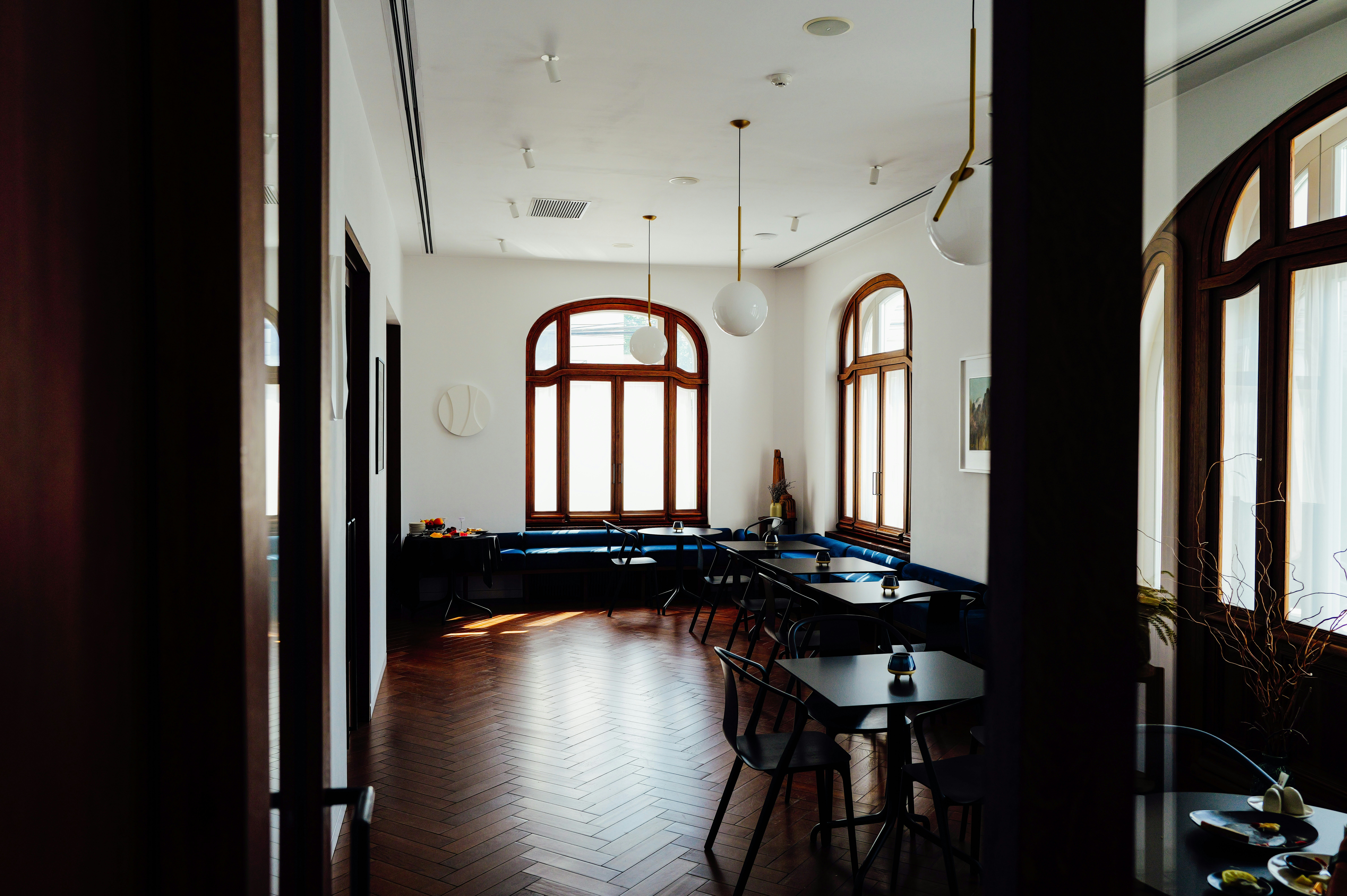 A restaurant interior with dark wooden floors, black tables, and arched windows - 相关推荐