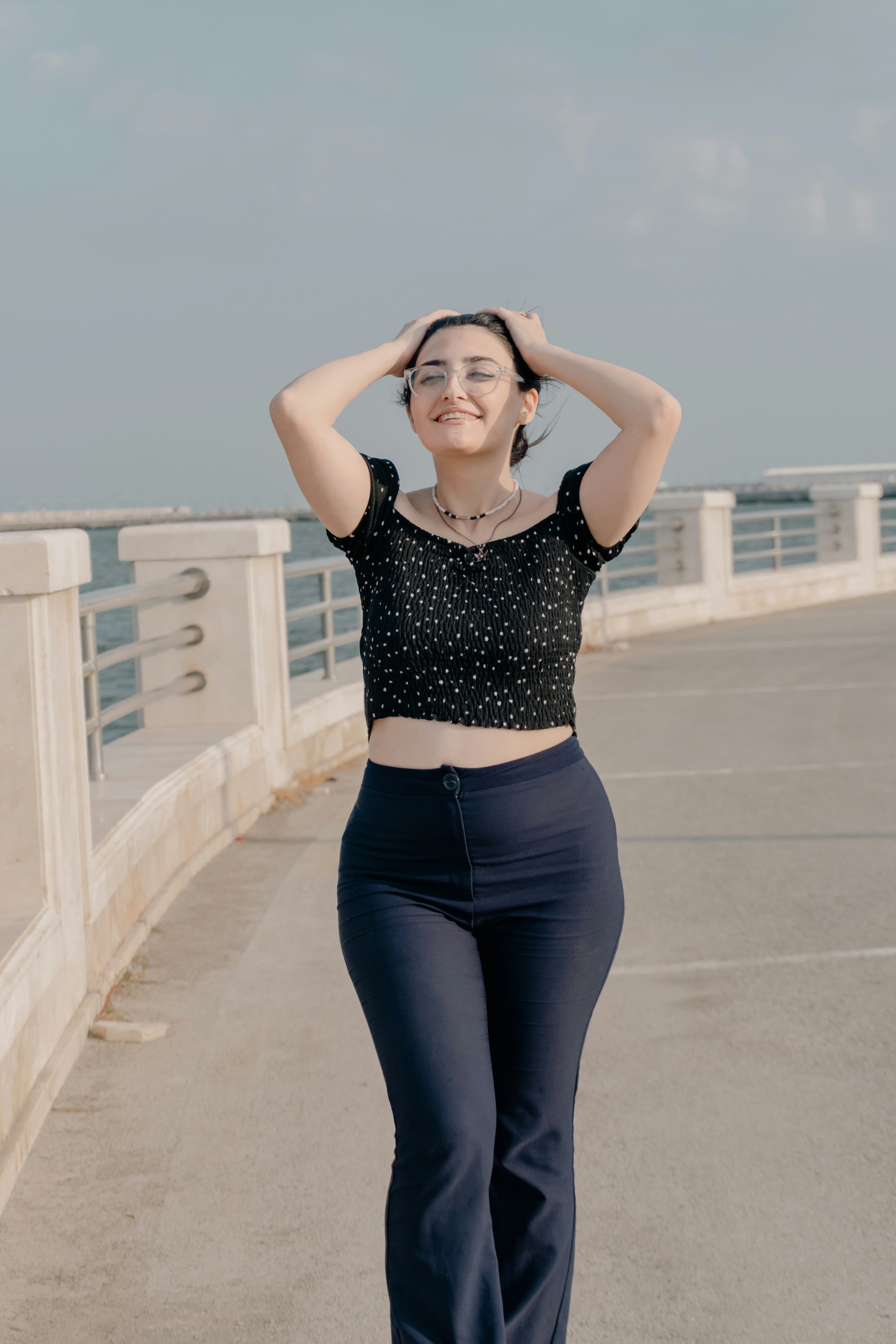 A woman in a black polka dot top and dark trousers walking outdoors