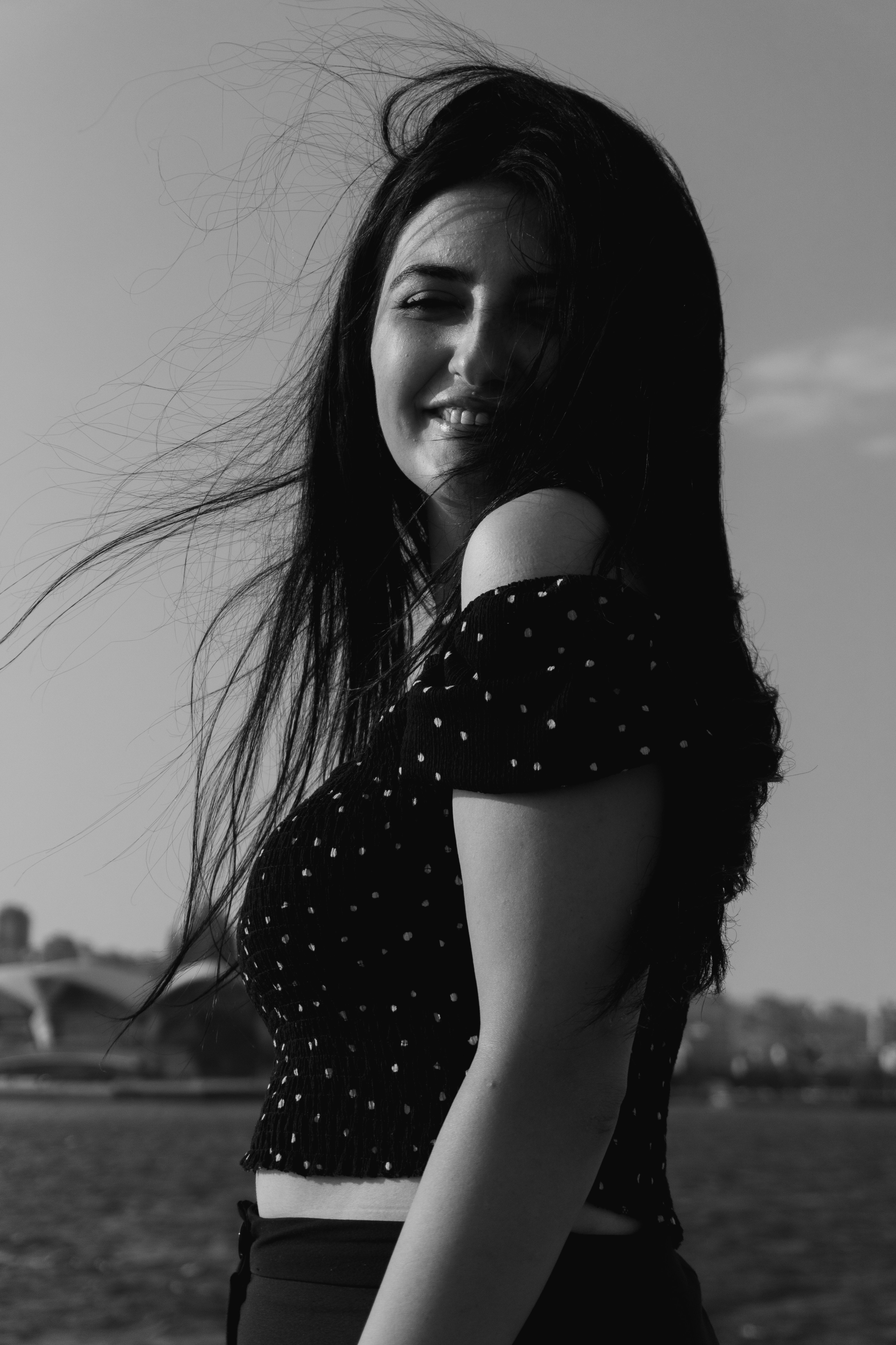 A woman in a polka dot off-shoulder top with hair blowing in the wind