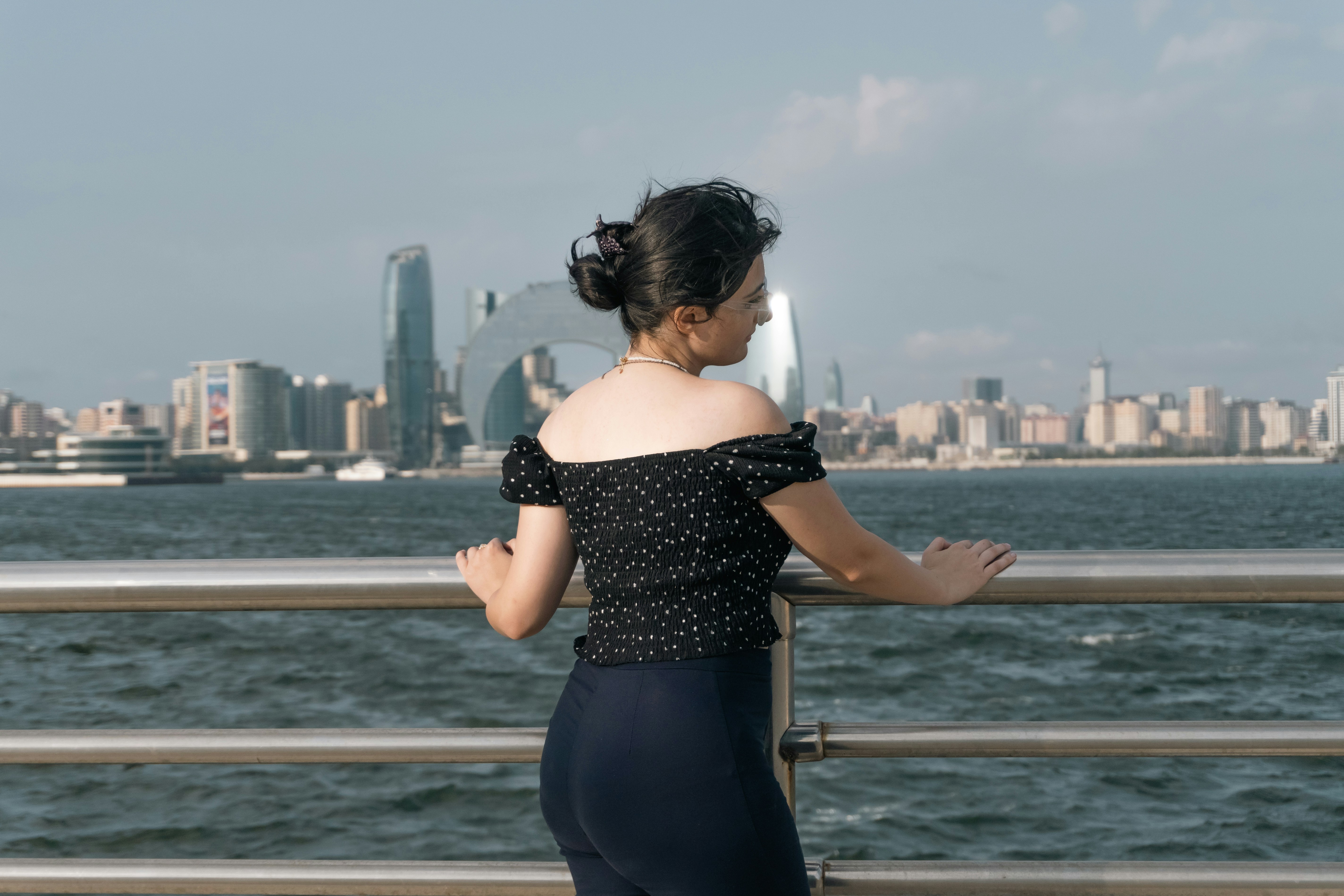 A woman in a black polka dot top leaning on a railing overlooking Baku