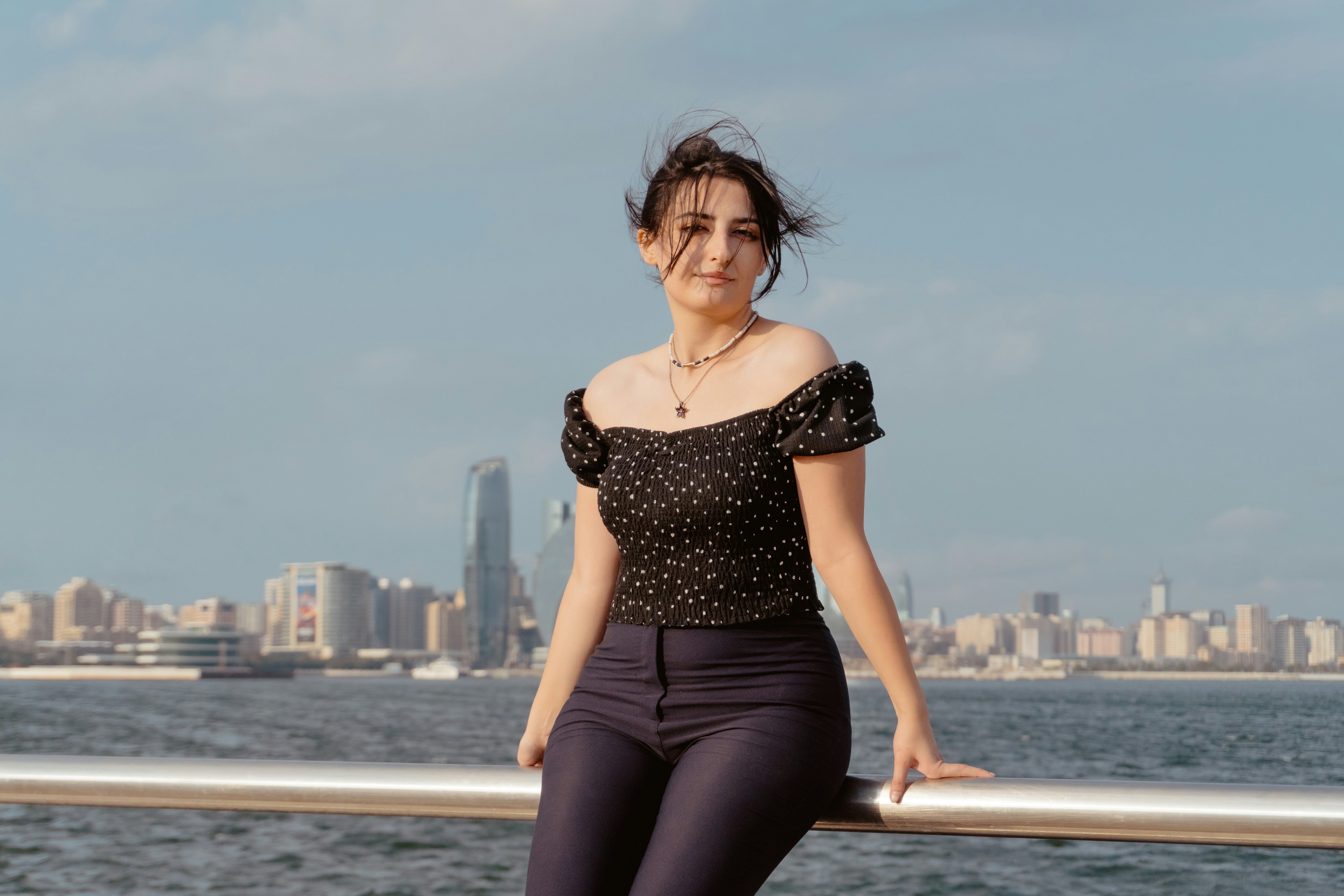 A woman in a black polka dot top leaning against a metal railing