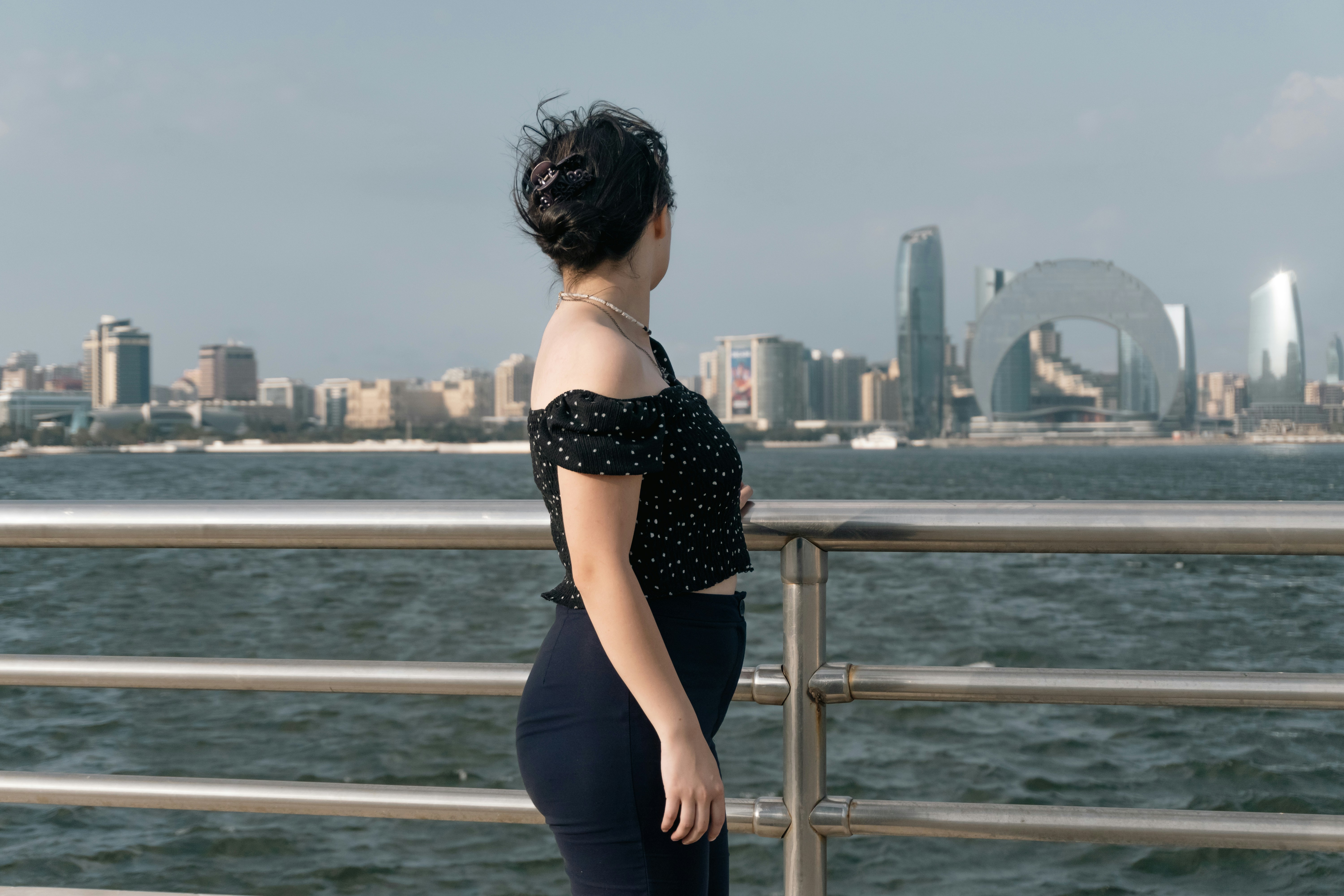 A woman in a black polka dot top looking at the Baku skyline