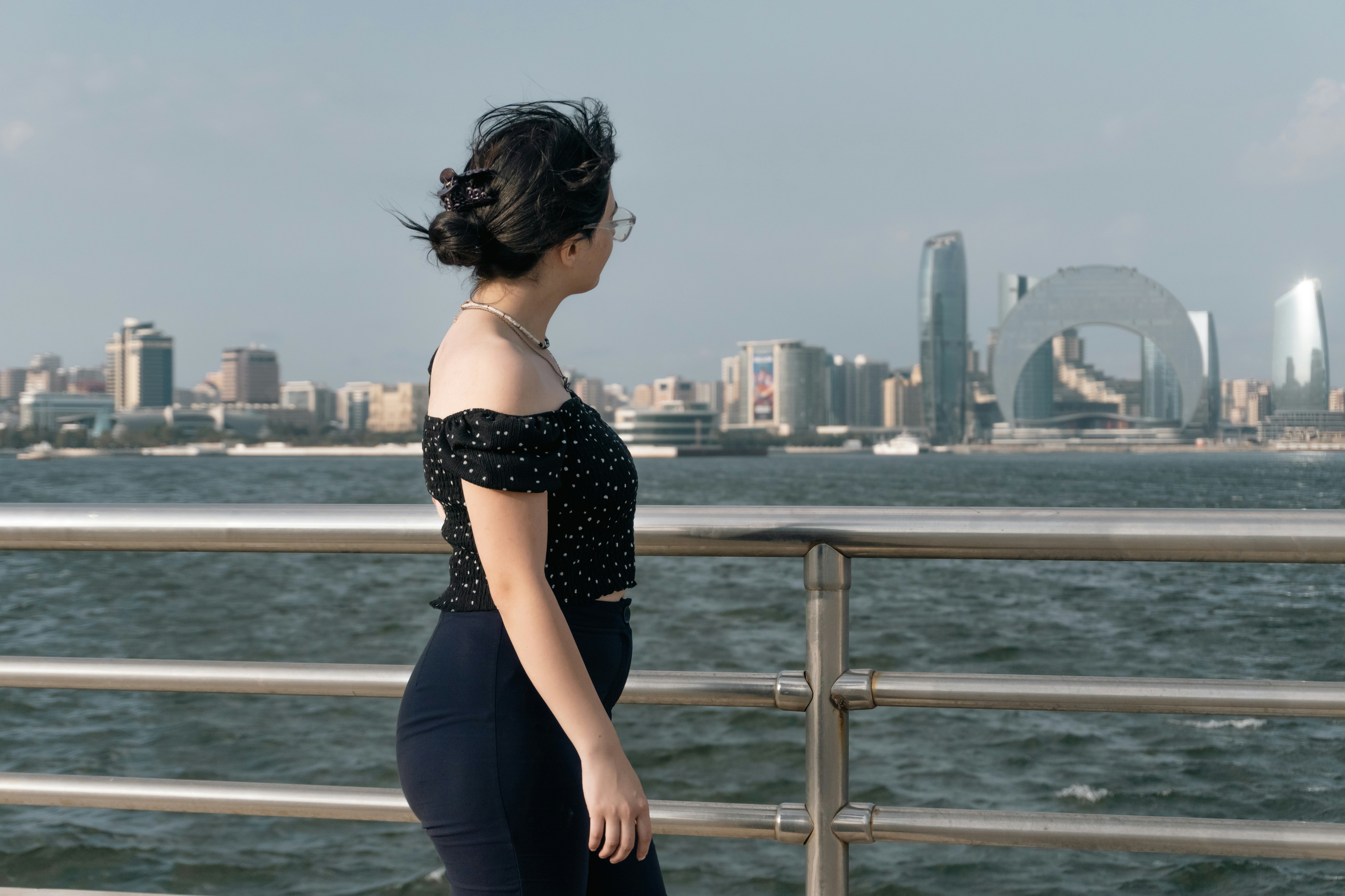 A woman in a black polka dot top looking at the Baku skyline