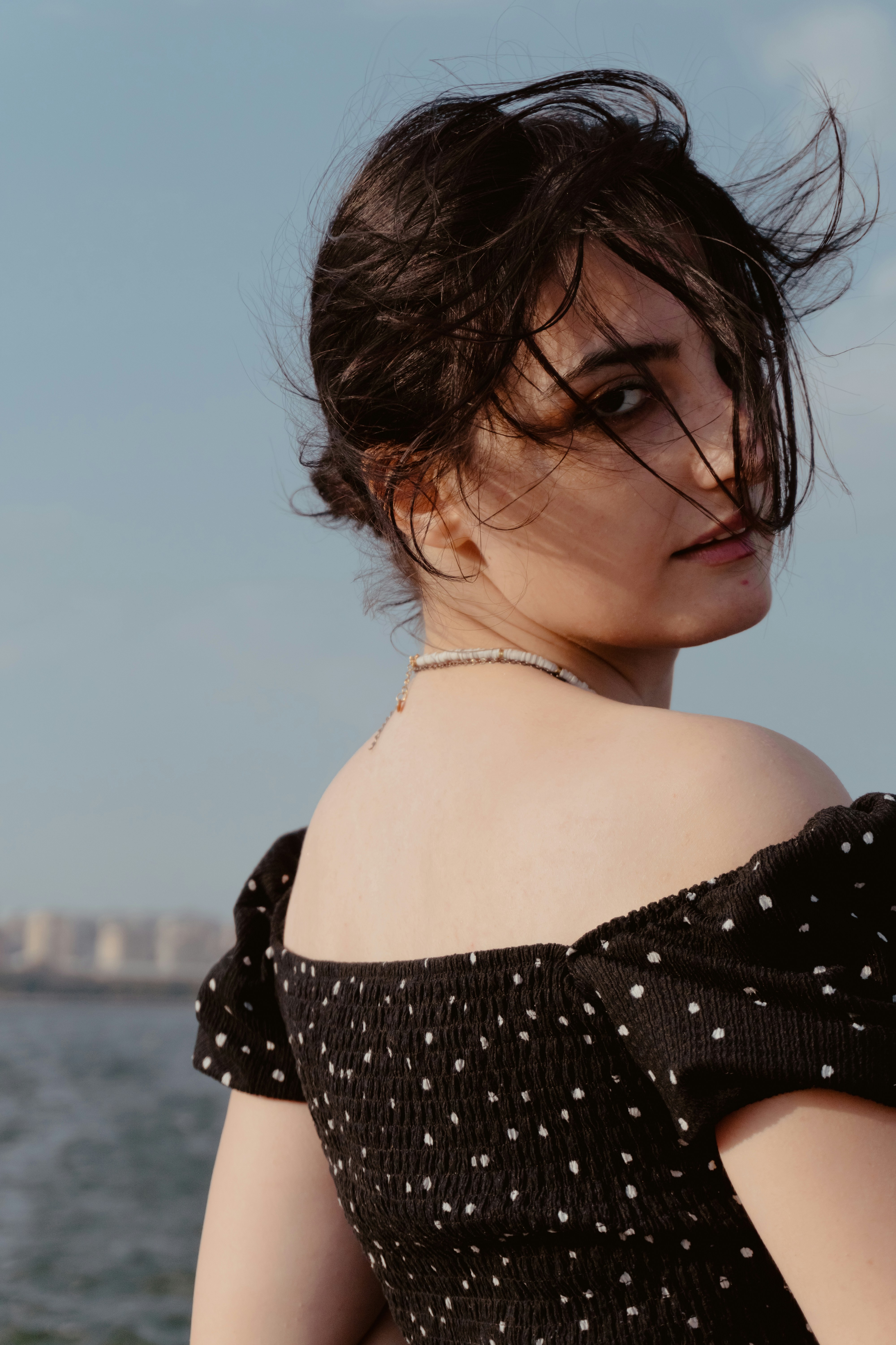 A woman in a black polka dot top looking back over her shoulder