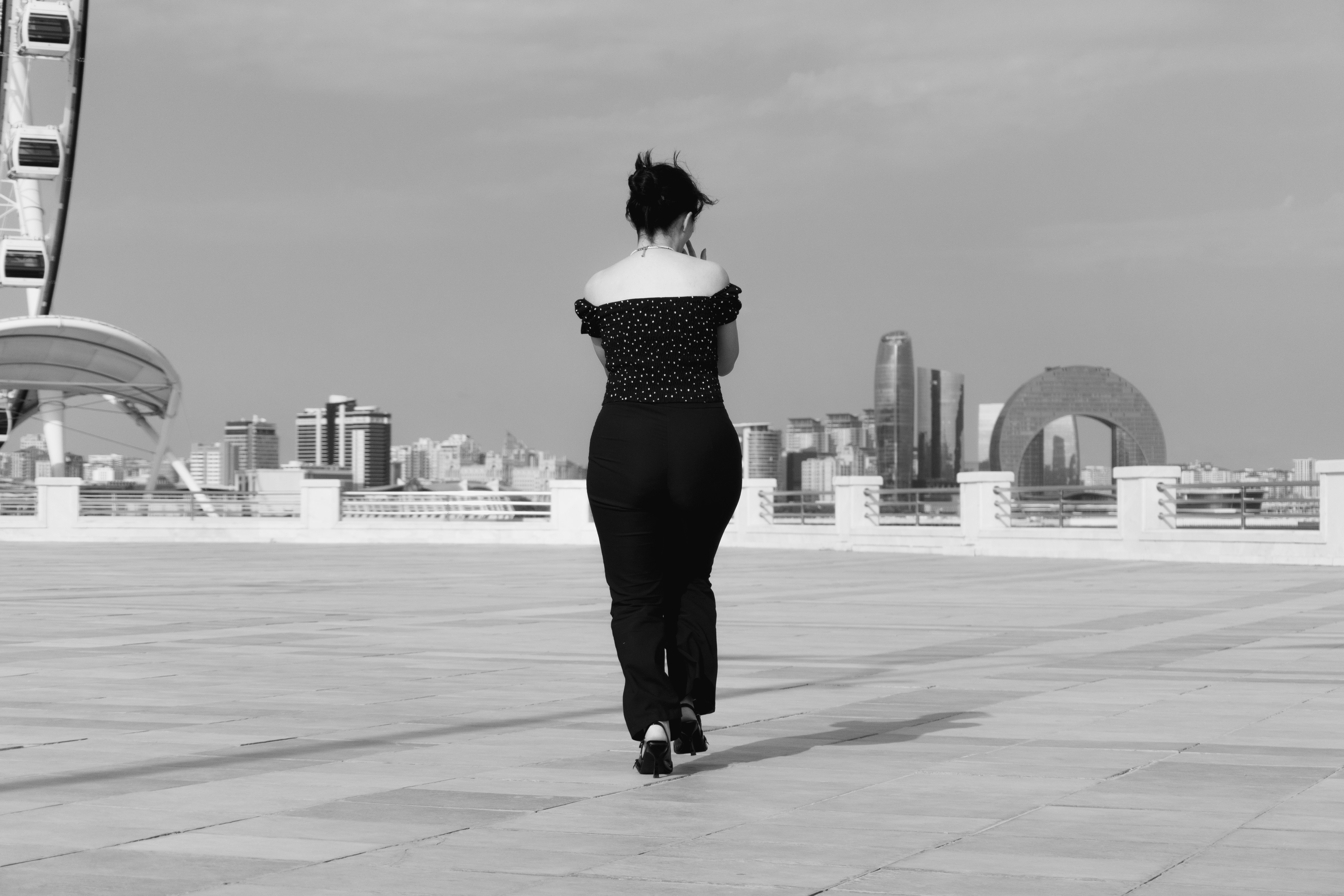 A woman in a polka dot top walking on a plaza in Baku