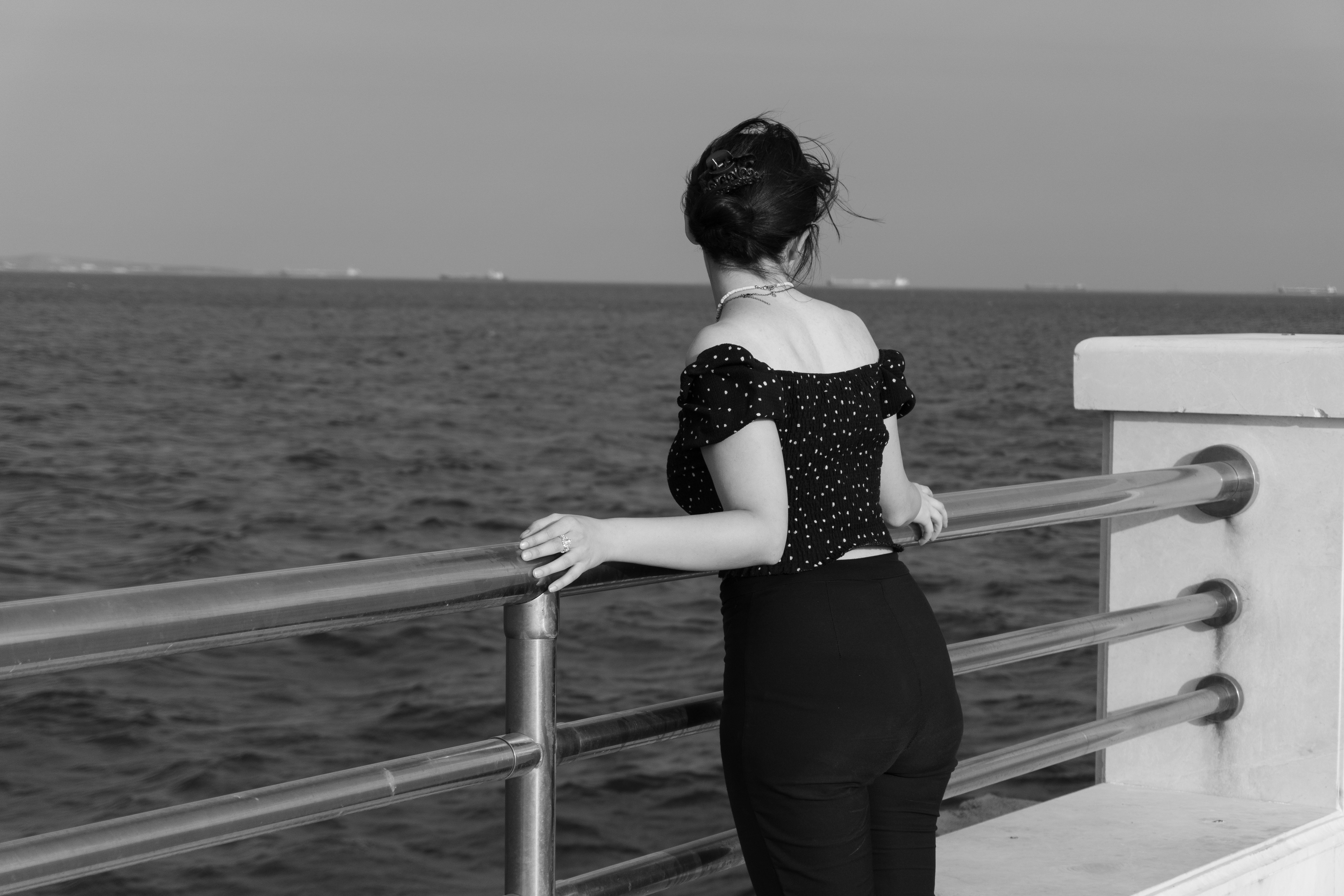 A woman in a polka dot top leaning on a metal railing overlooking water