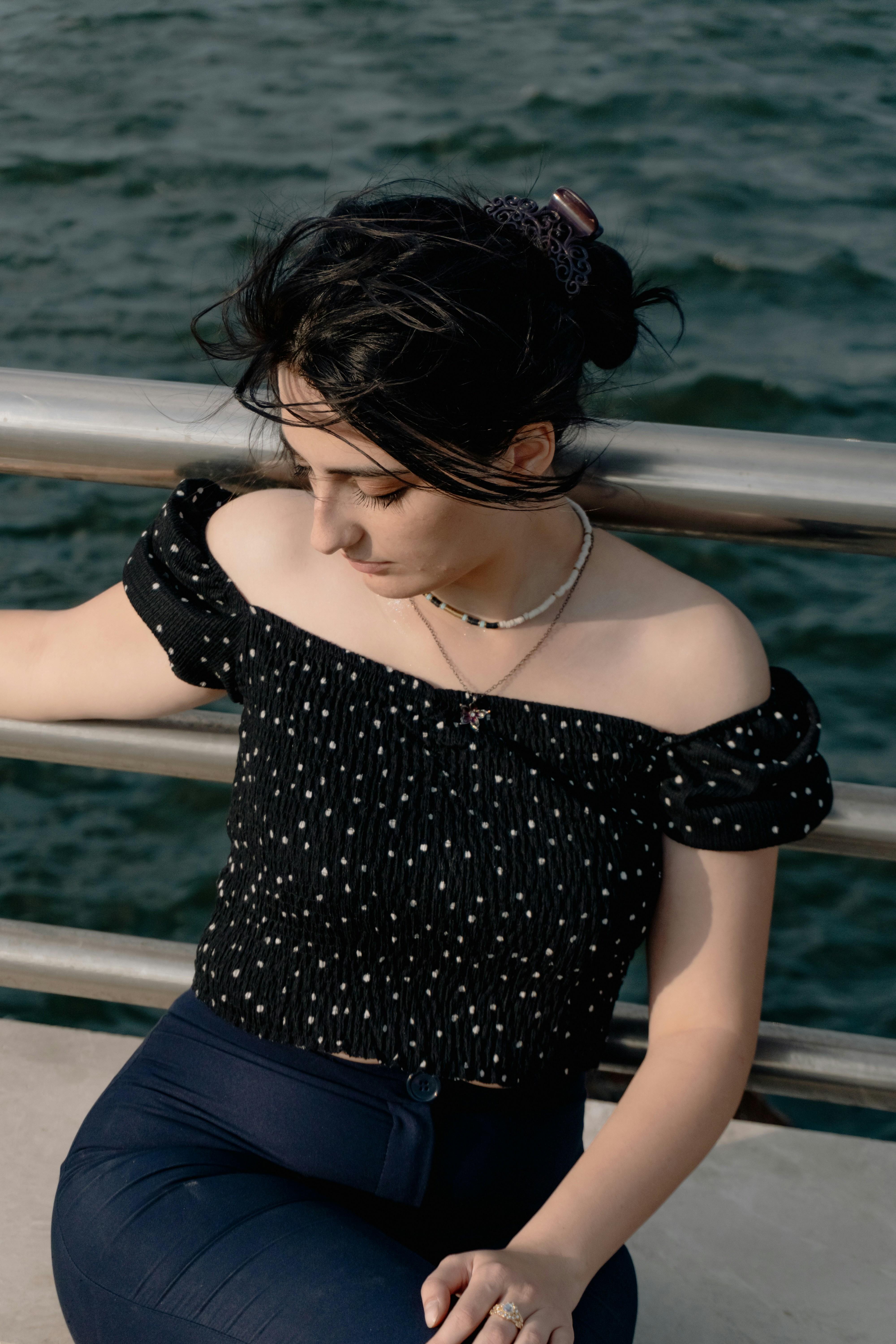 A woman in a black polka dot top leaning against a metal railing