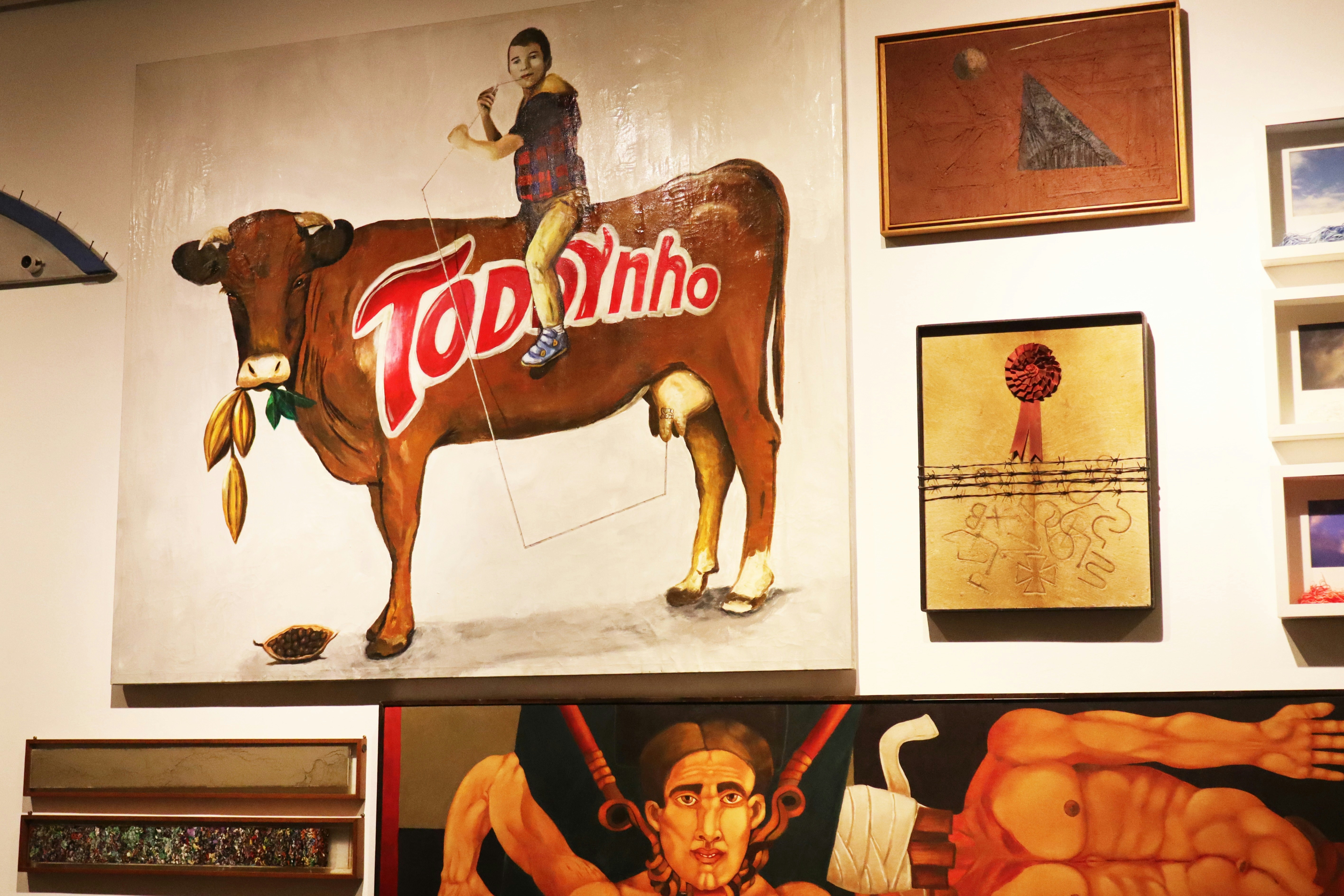 A painting of a child riding a brown cow with the word Toddyinho