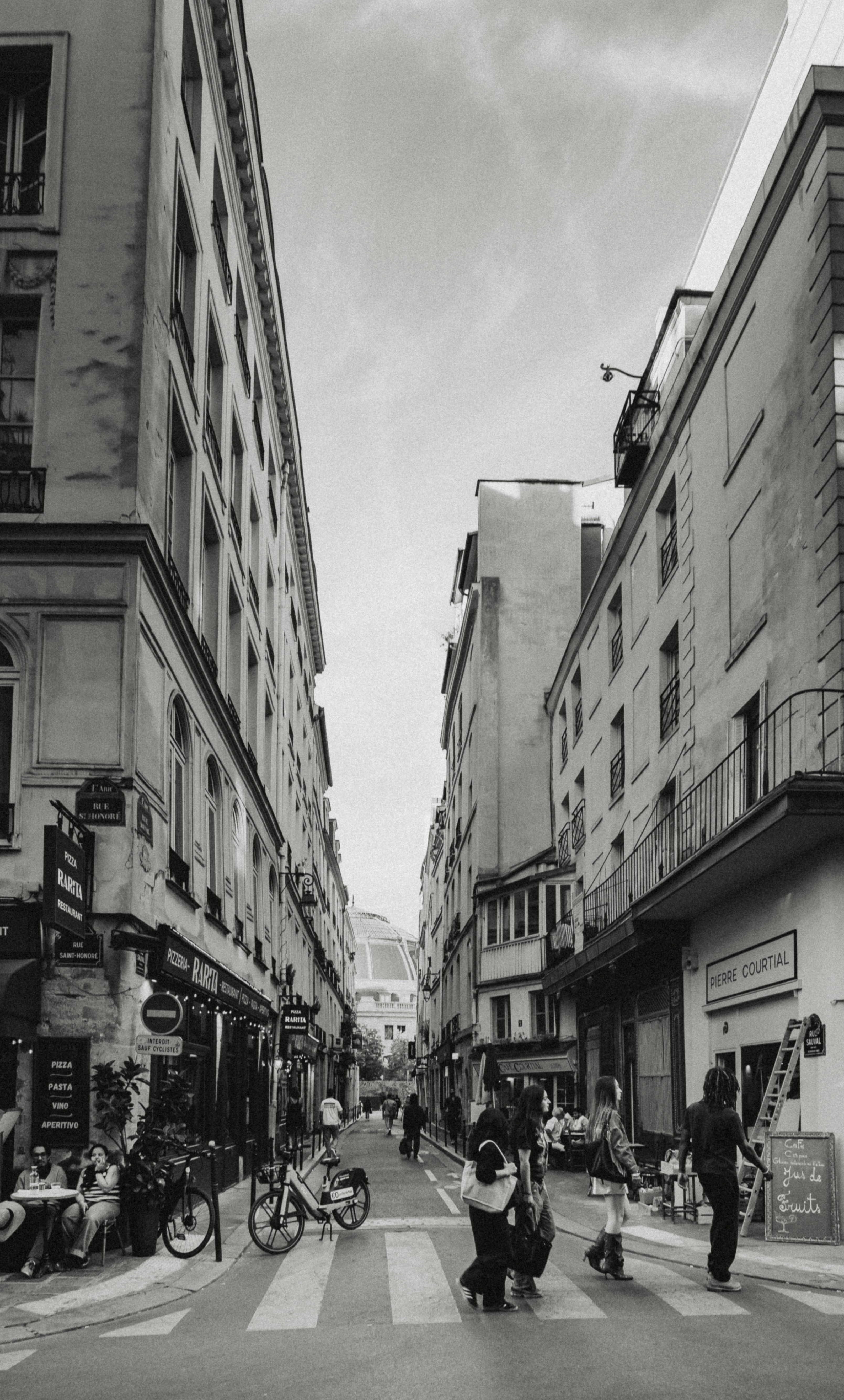 People walking on a narrow street with historic buildings in Paris, France