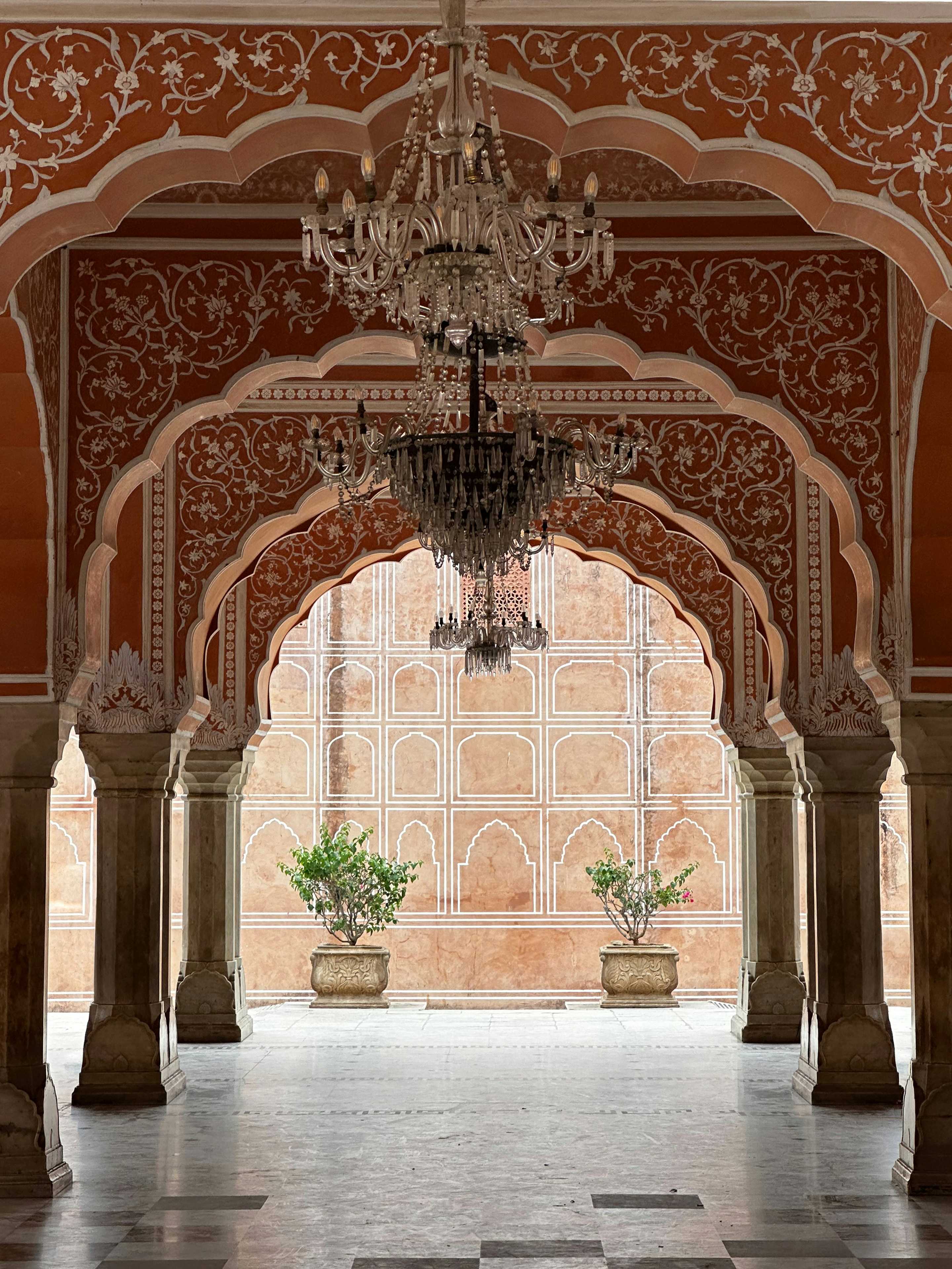 Ornate arches with white floral patterns framing a courtyard with two potted plants