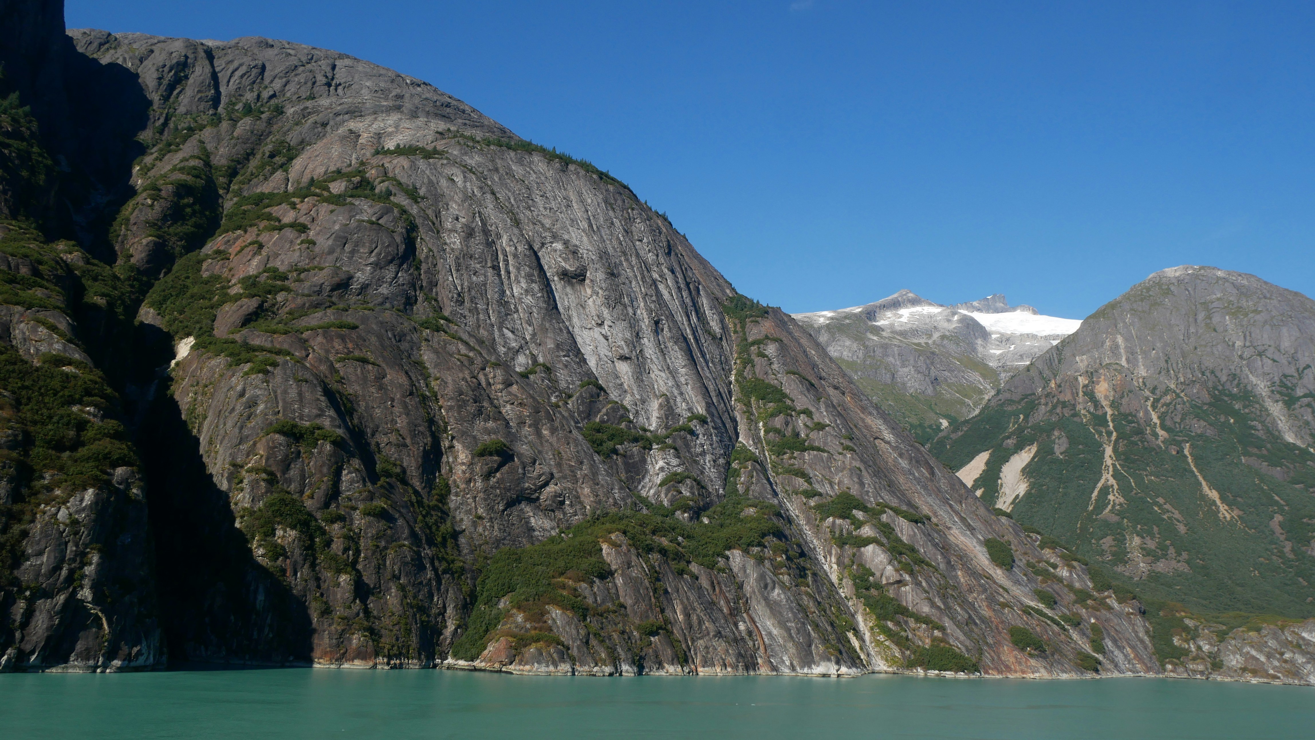 Steep rocky cliffs rising above turquoise water under a clear blue sky