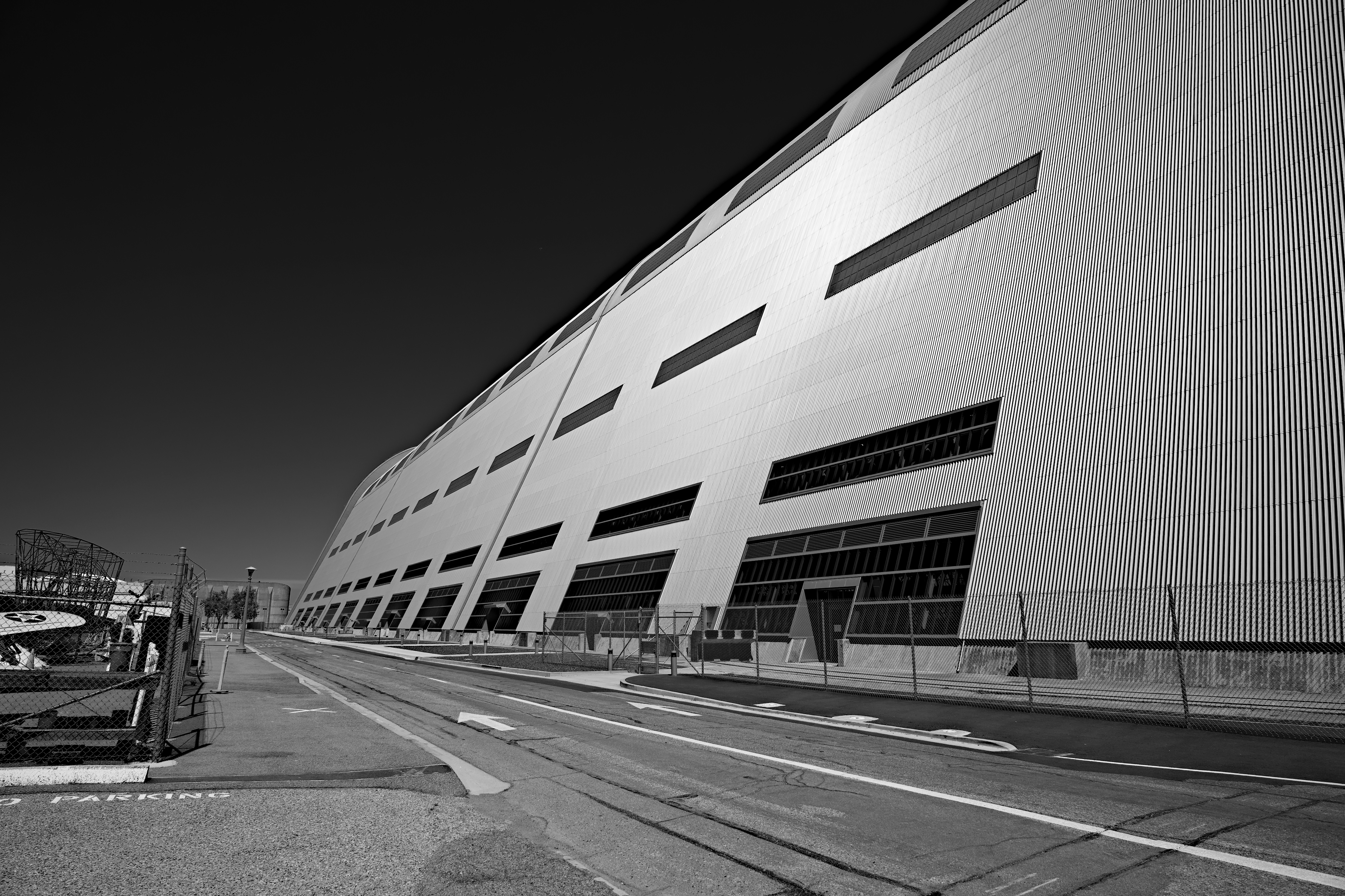 A large industrial building with corrugated metal walls beside an empty asphalt road