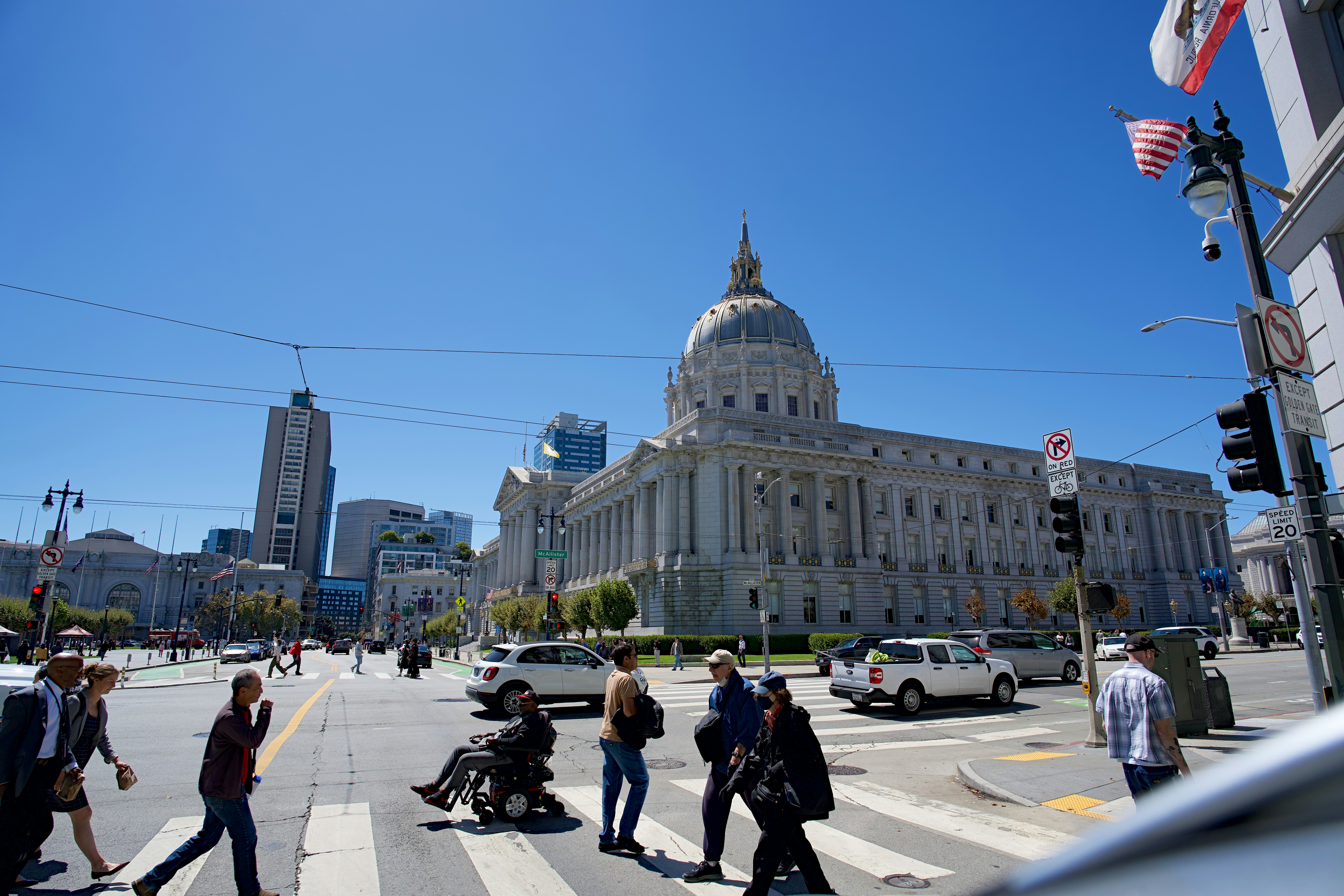 People crossing a street in front of San Francisco City Hall on a sunny day