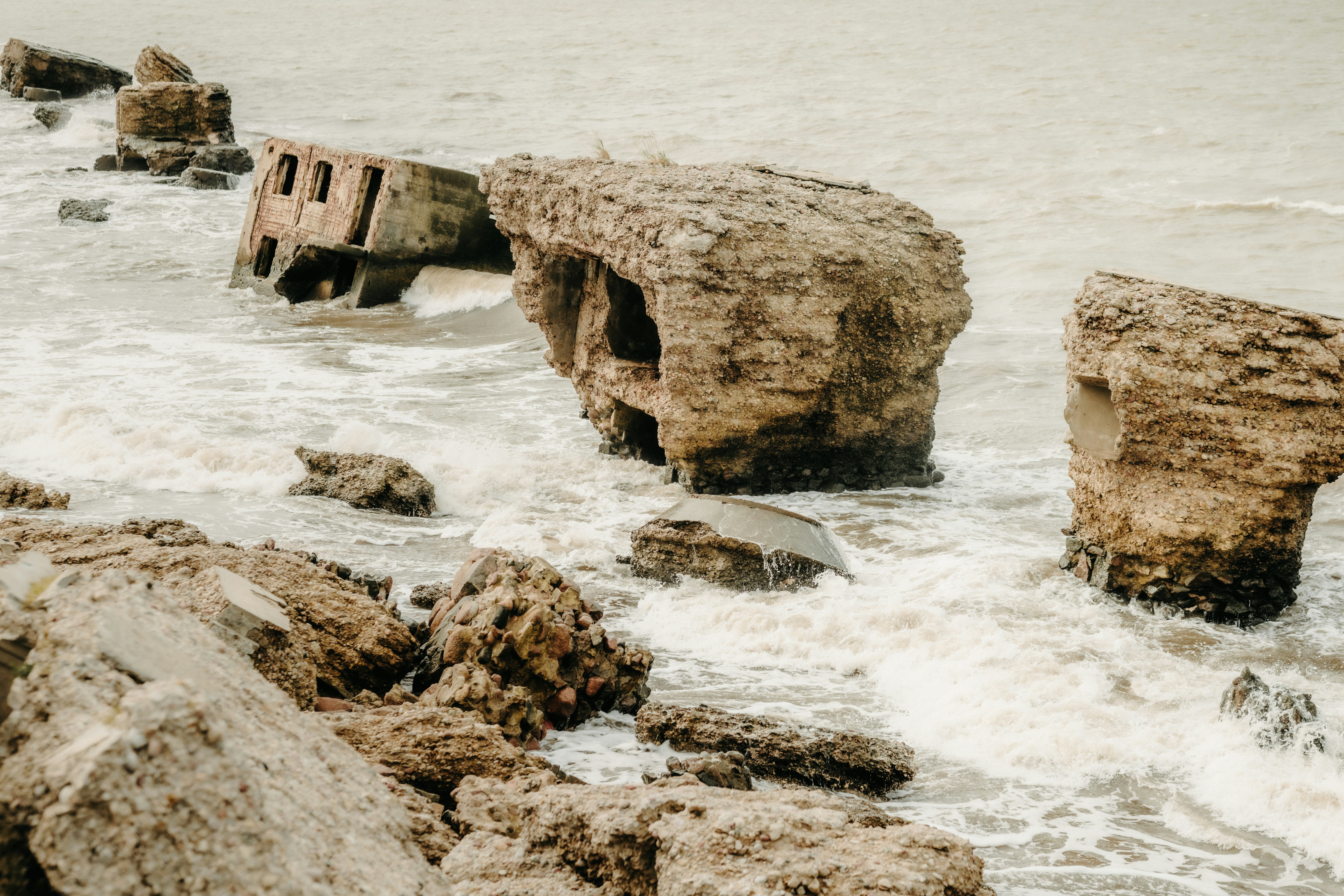 Ruined concrete bunkers in the surf along a rocky coastline