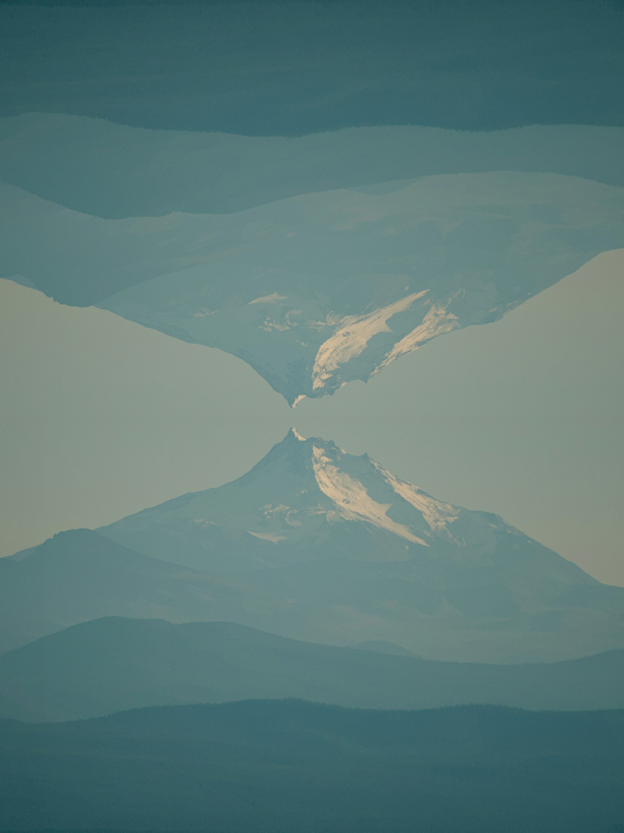 A mirrored mountain peak with snow against a pale blue sky