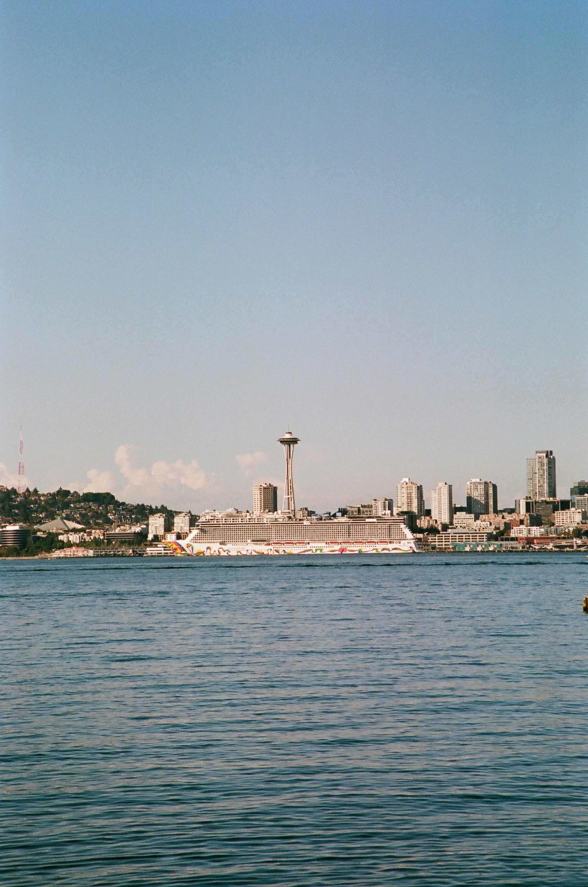 A large cruise ship docked before the Space Needle and Seattle skyline