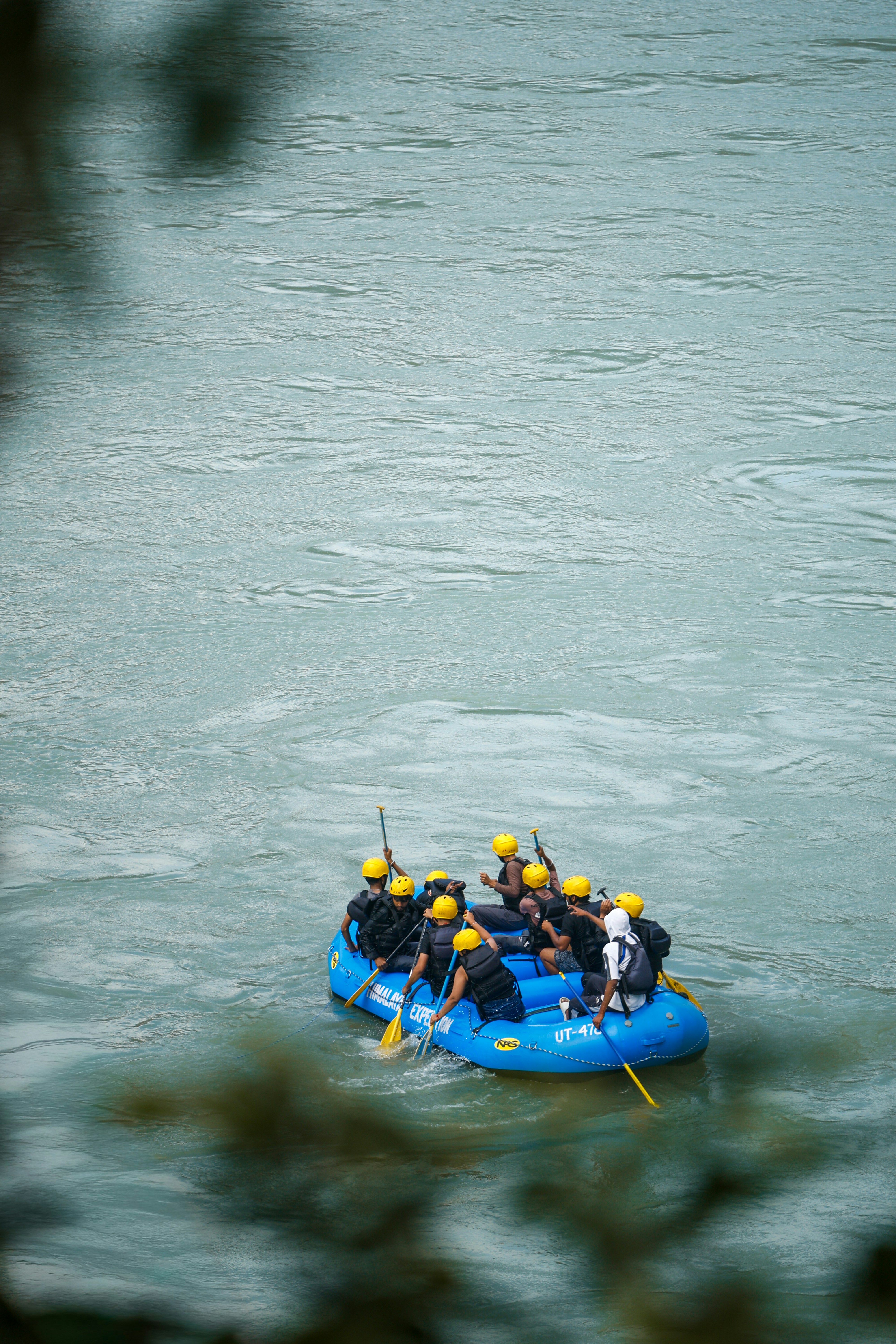 A group of people in yellow helmets whitewater rafting on a blue river