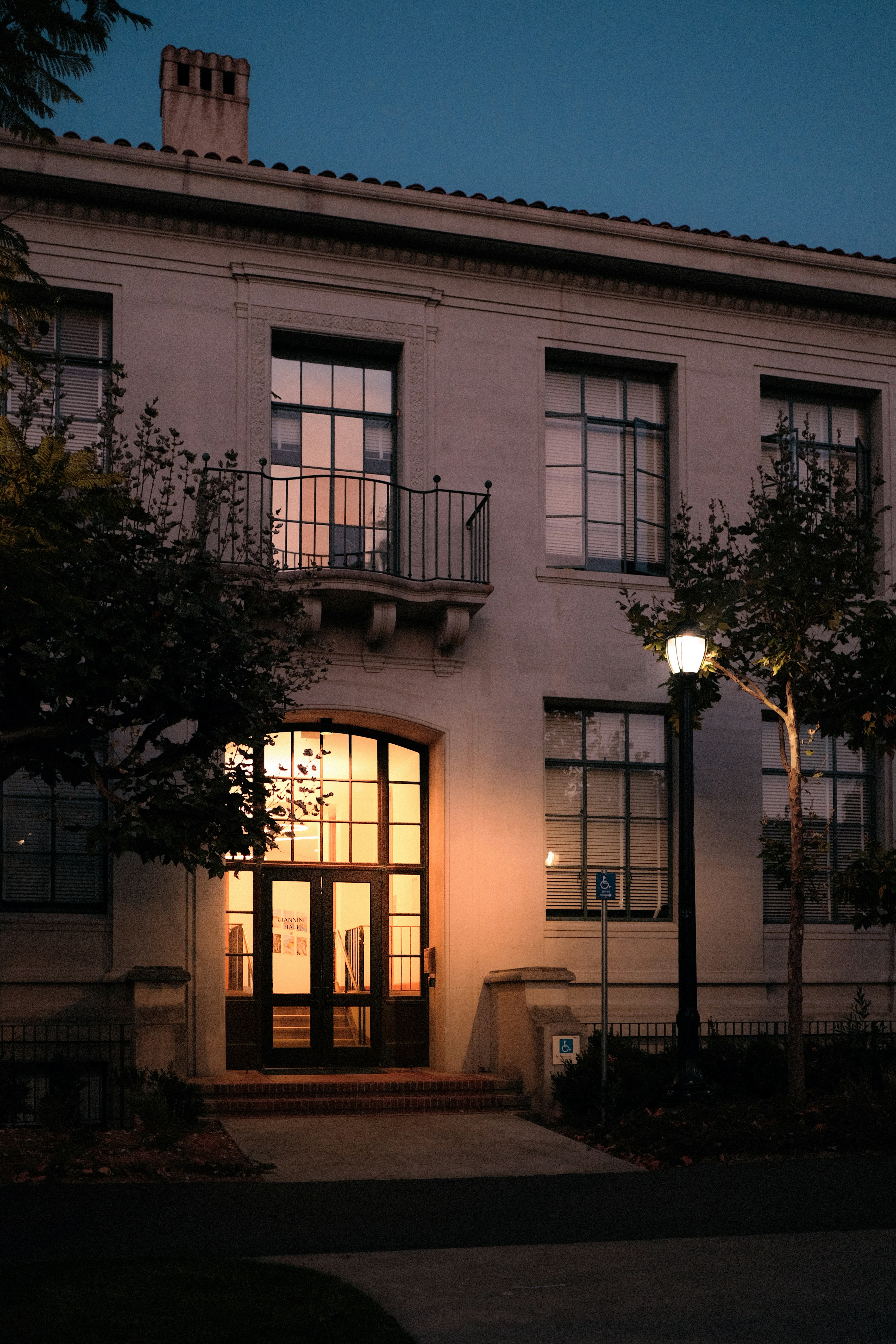 Giannini Hall entrance with warm interior lighting at dusk on a university campus