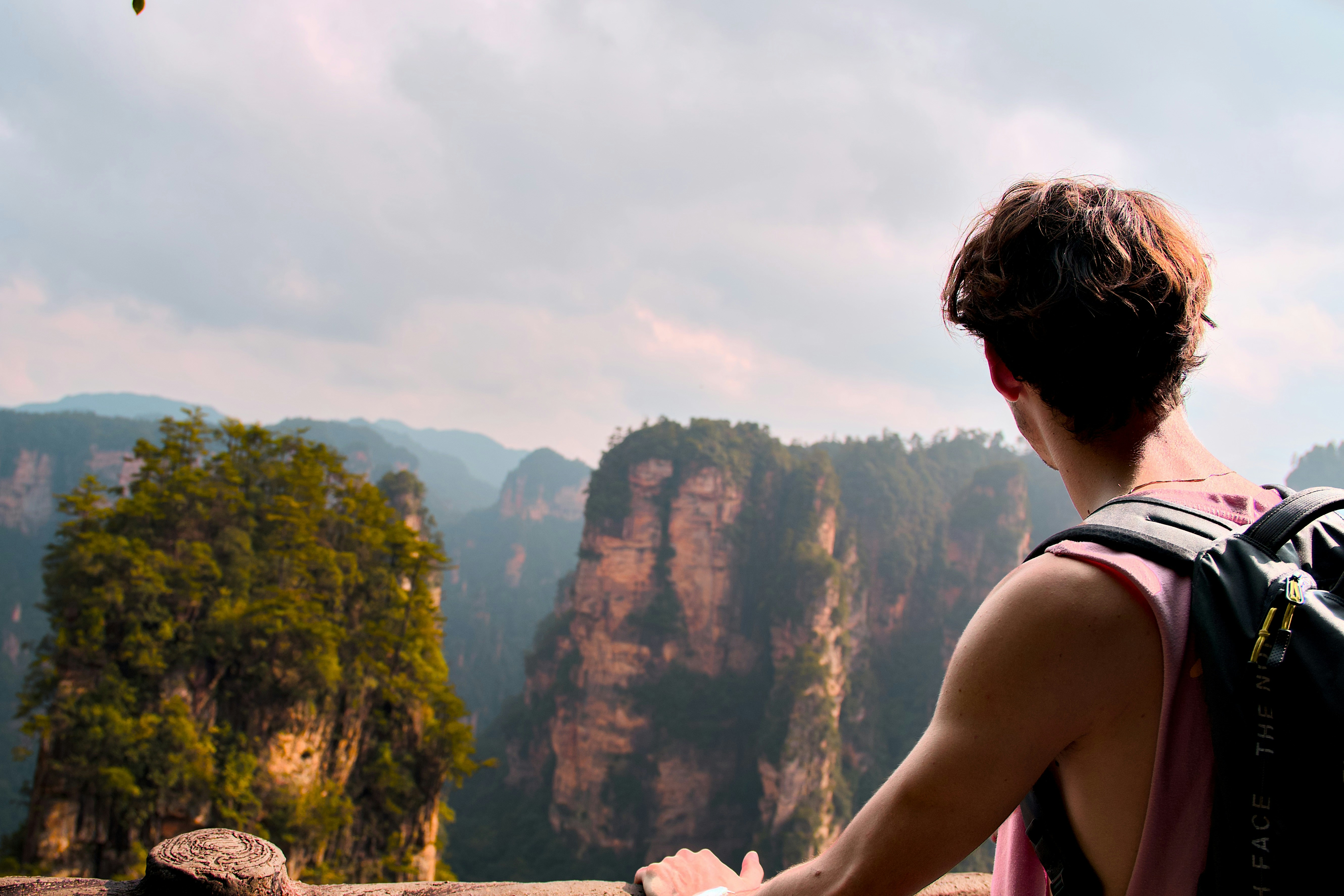 Una persona con una mochila mirando altos pilares de arenisca en Zhangjiajie