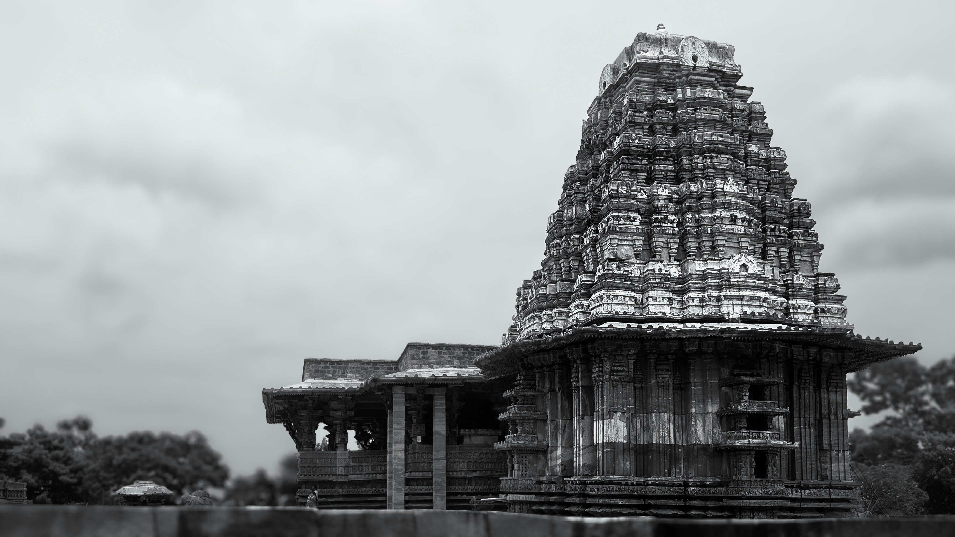 An ornate stone temple with a tiered tower under a cloudy sky