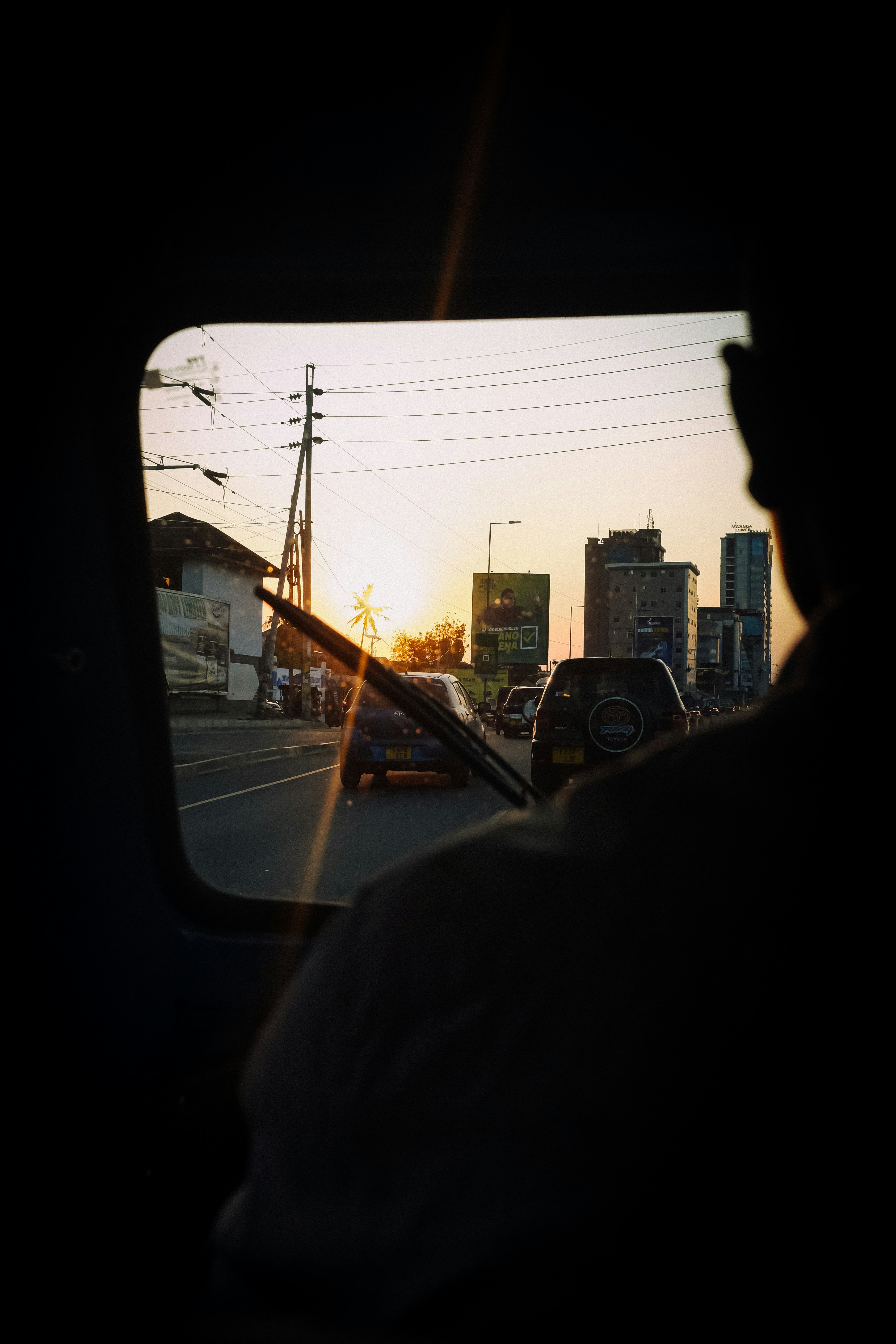 View from a vehicle window of city traffic at low sun