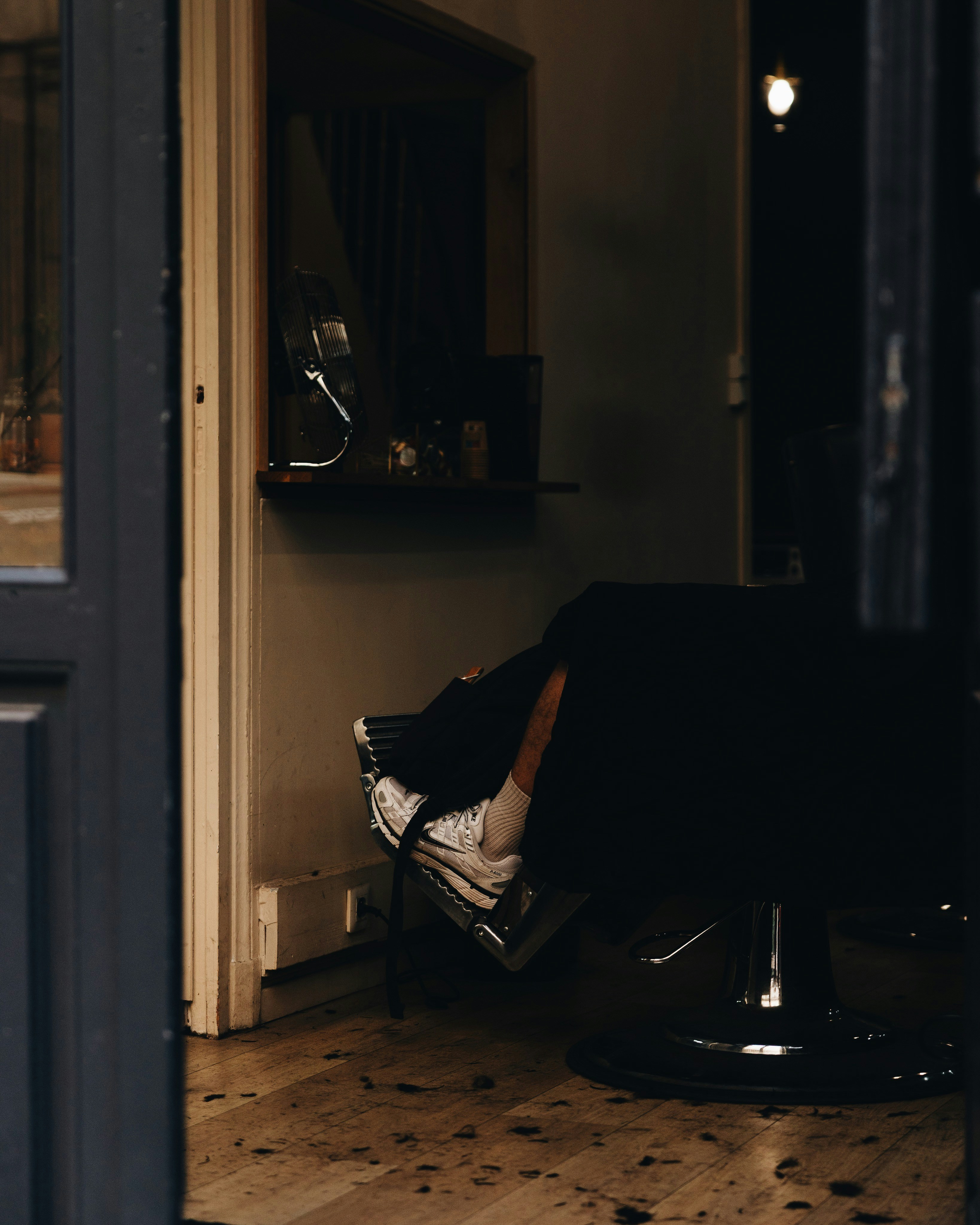 Une personne dans un fauteuil de barbier avec des baskets blanches sur un repose-pieds
