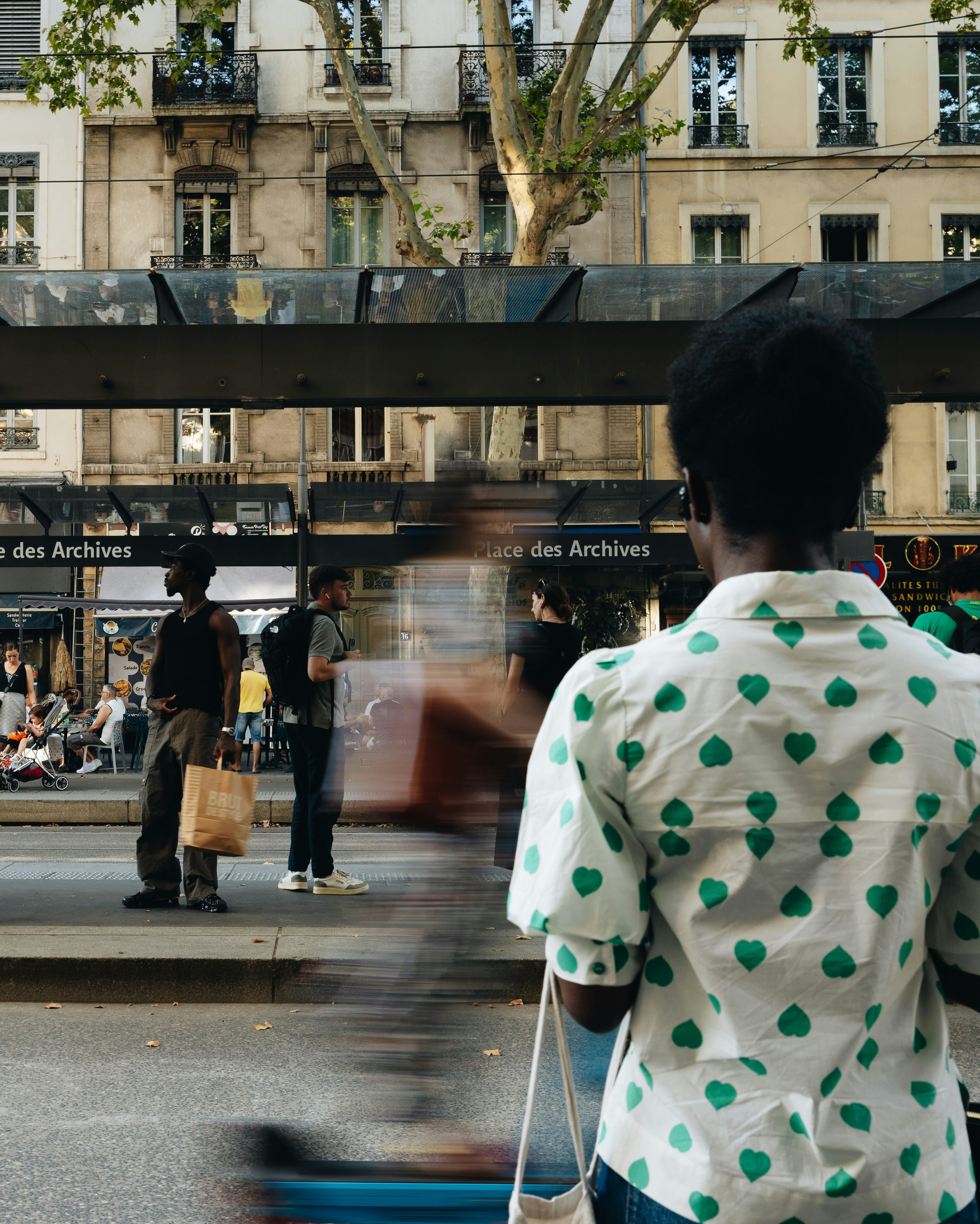 Des personnes attendant à une station de tramway près de la Place des Archives à Lyon