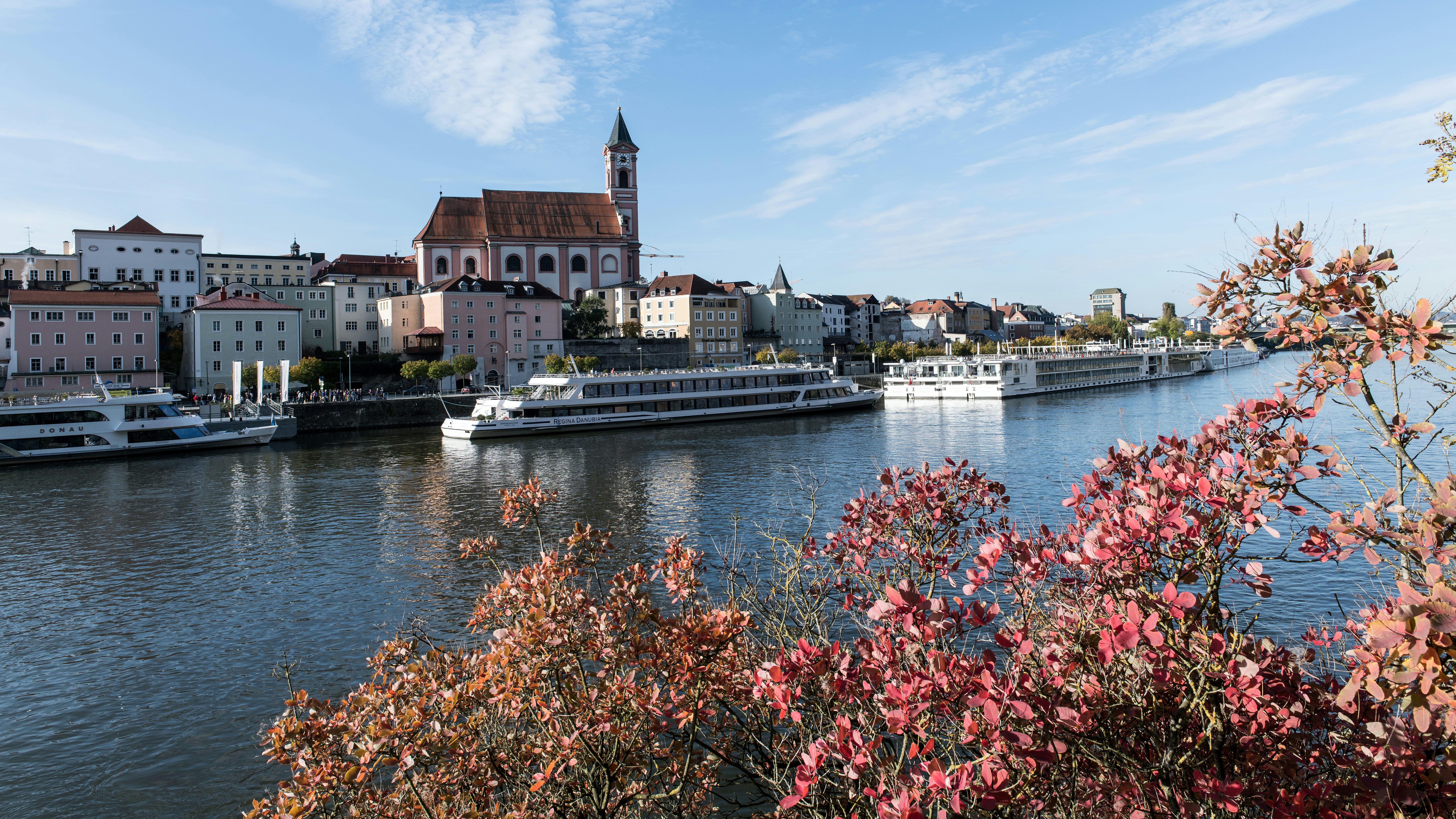 River cruise ships docked along a historic town with a church in Passau