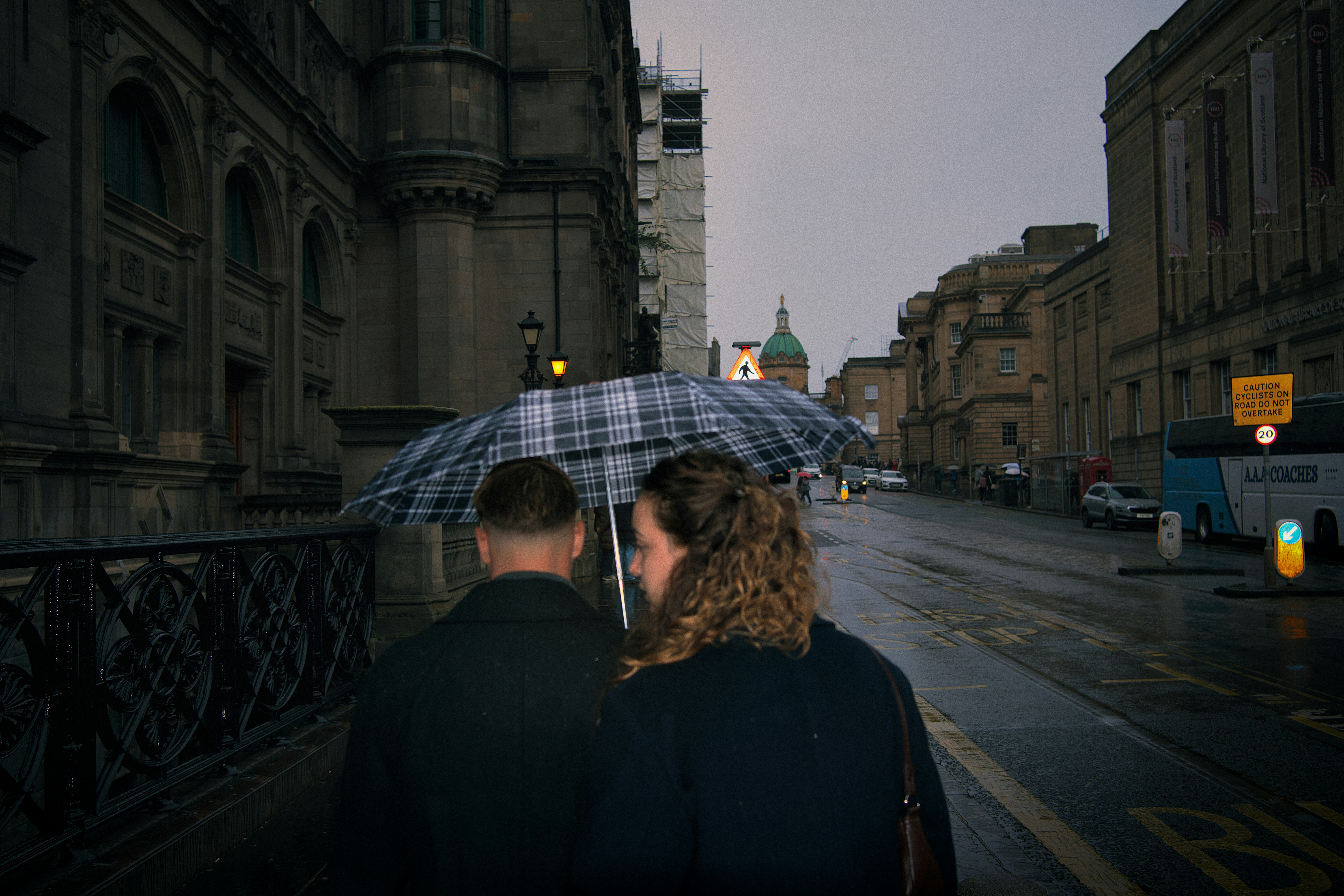 Couple walking under a plaid umbrella