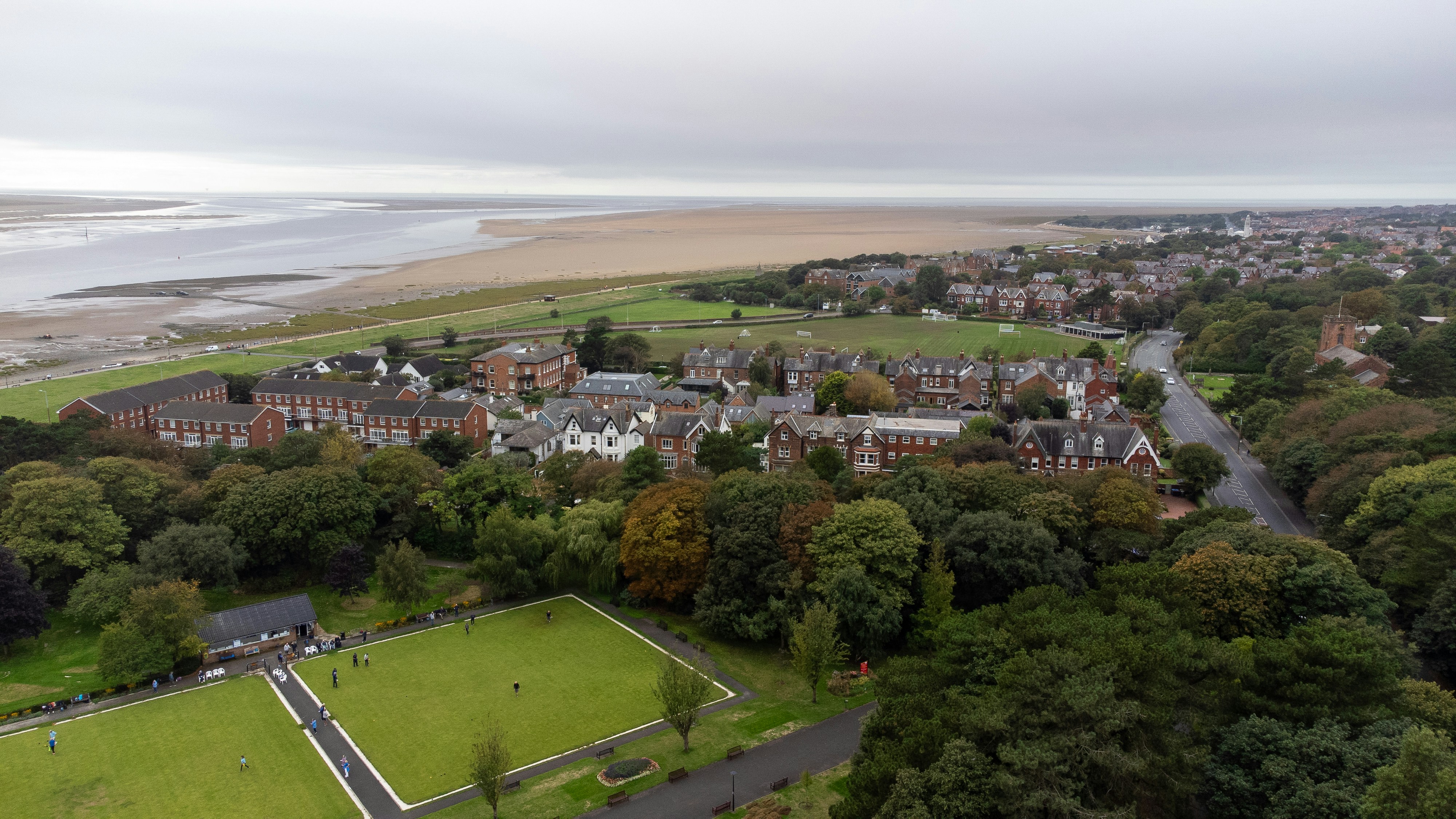 Aerial view of a coastal town with red brick houses near a sandy beach