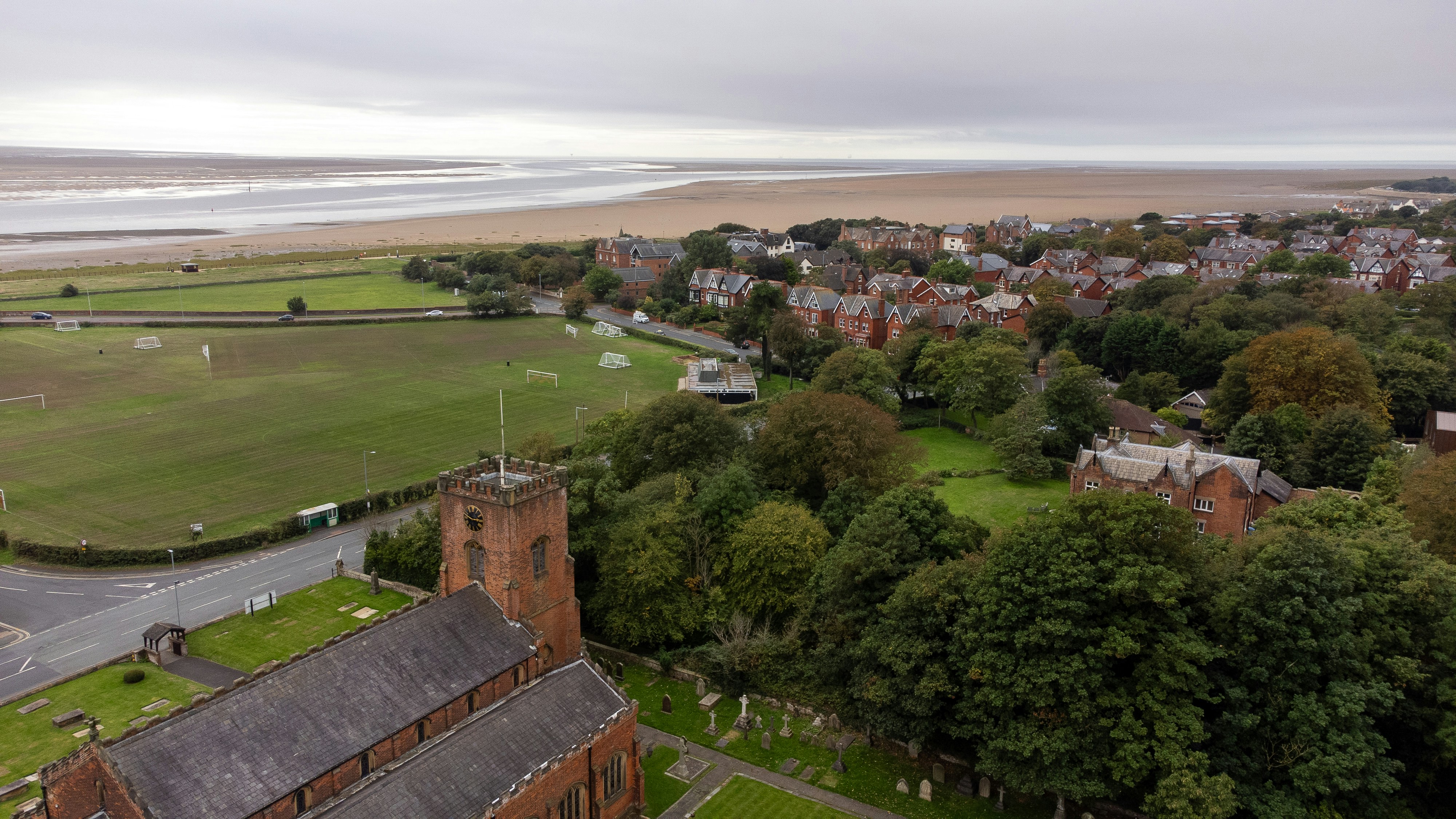 An aerial view of a brick church, a cemetery, and a coastal town
