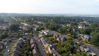 An aerial view of a suburban neighborhood with winding roads and dense green trees
