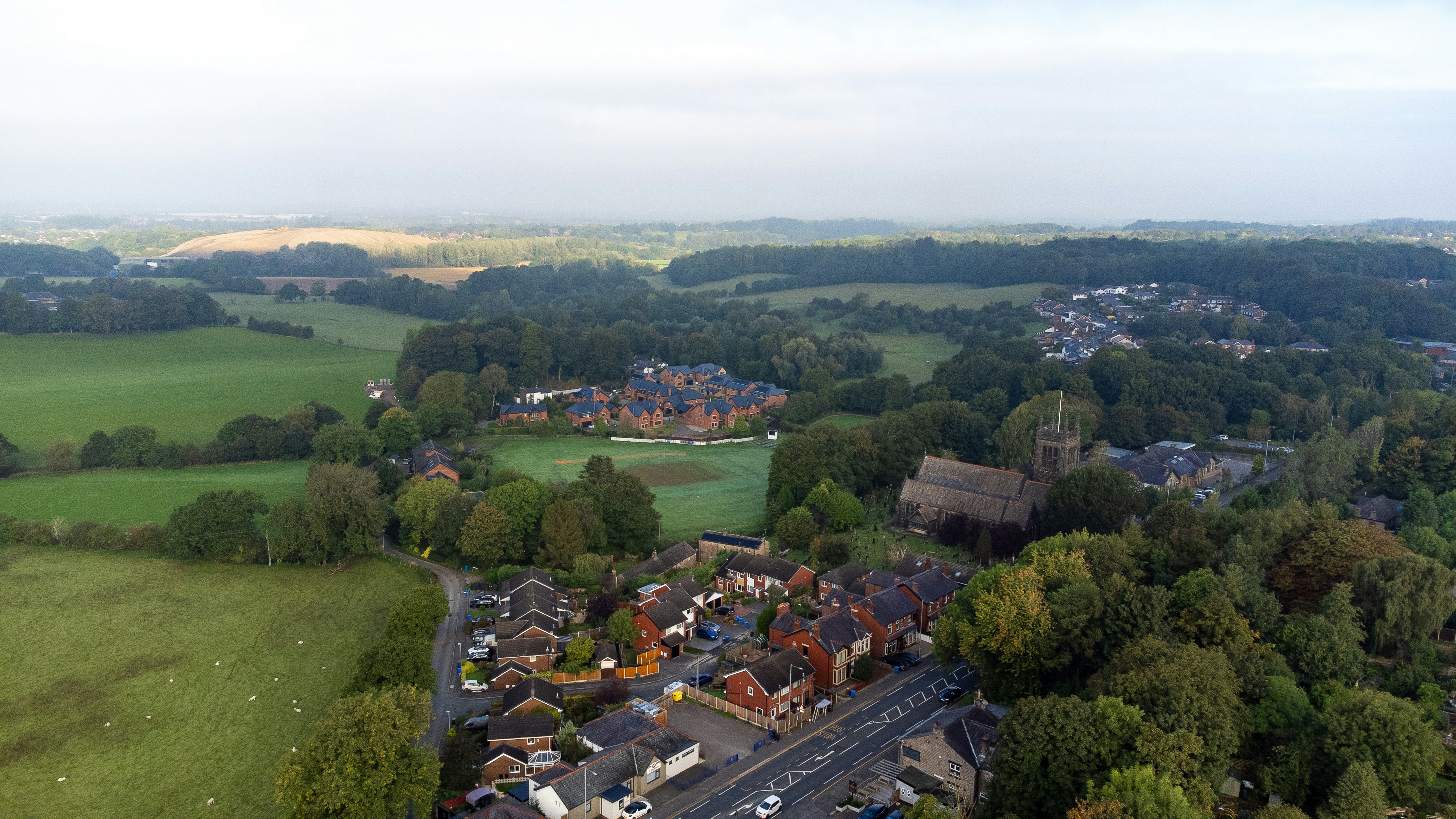 Aerial view of a village with a stone church surrounded by green fields