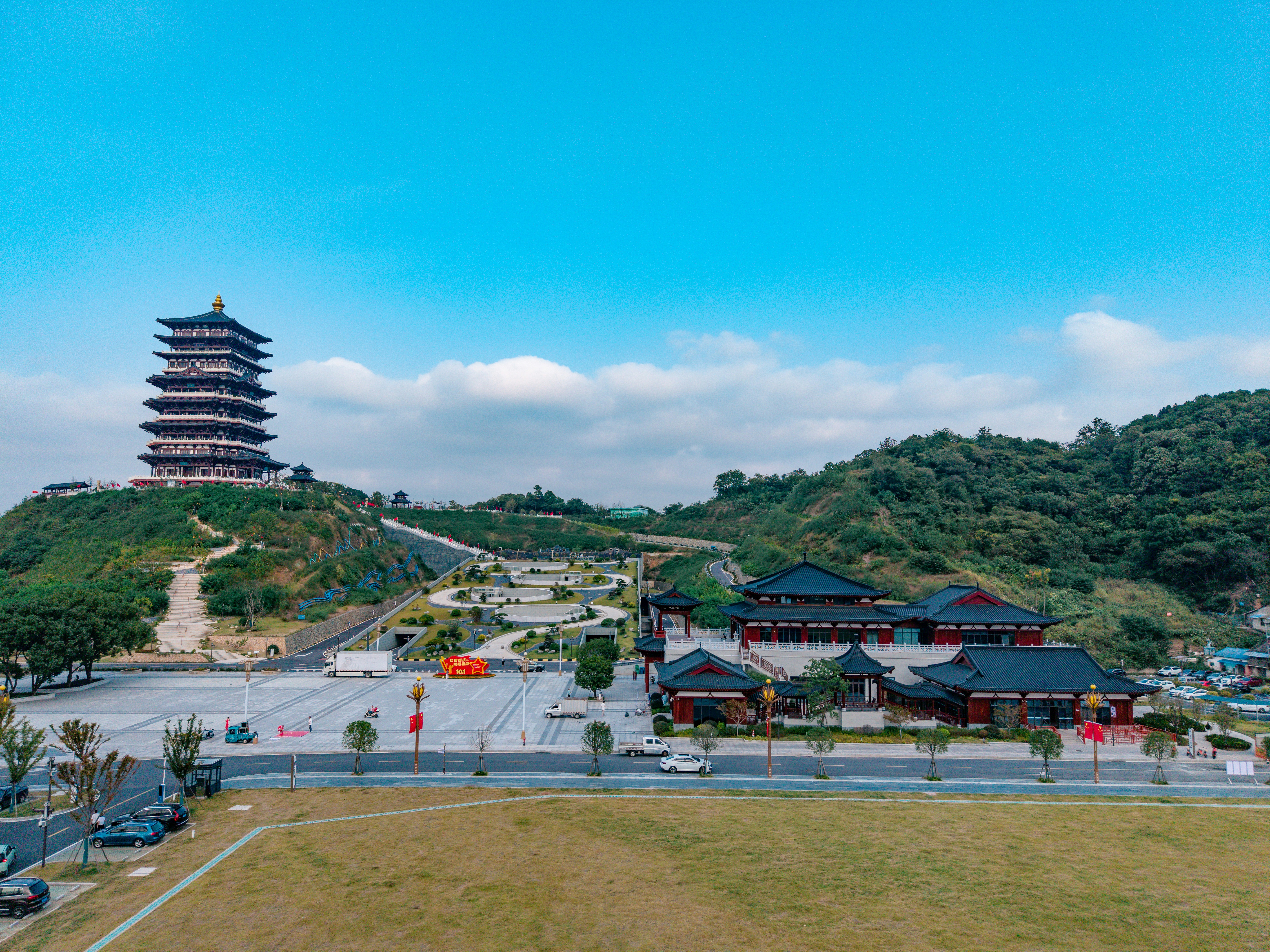 A tall pagoda on a hill overlooking a park and traditional buildings