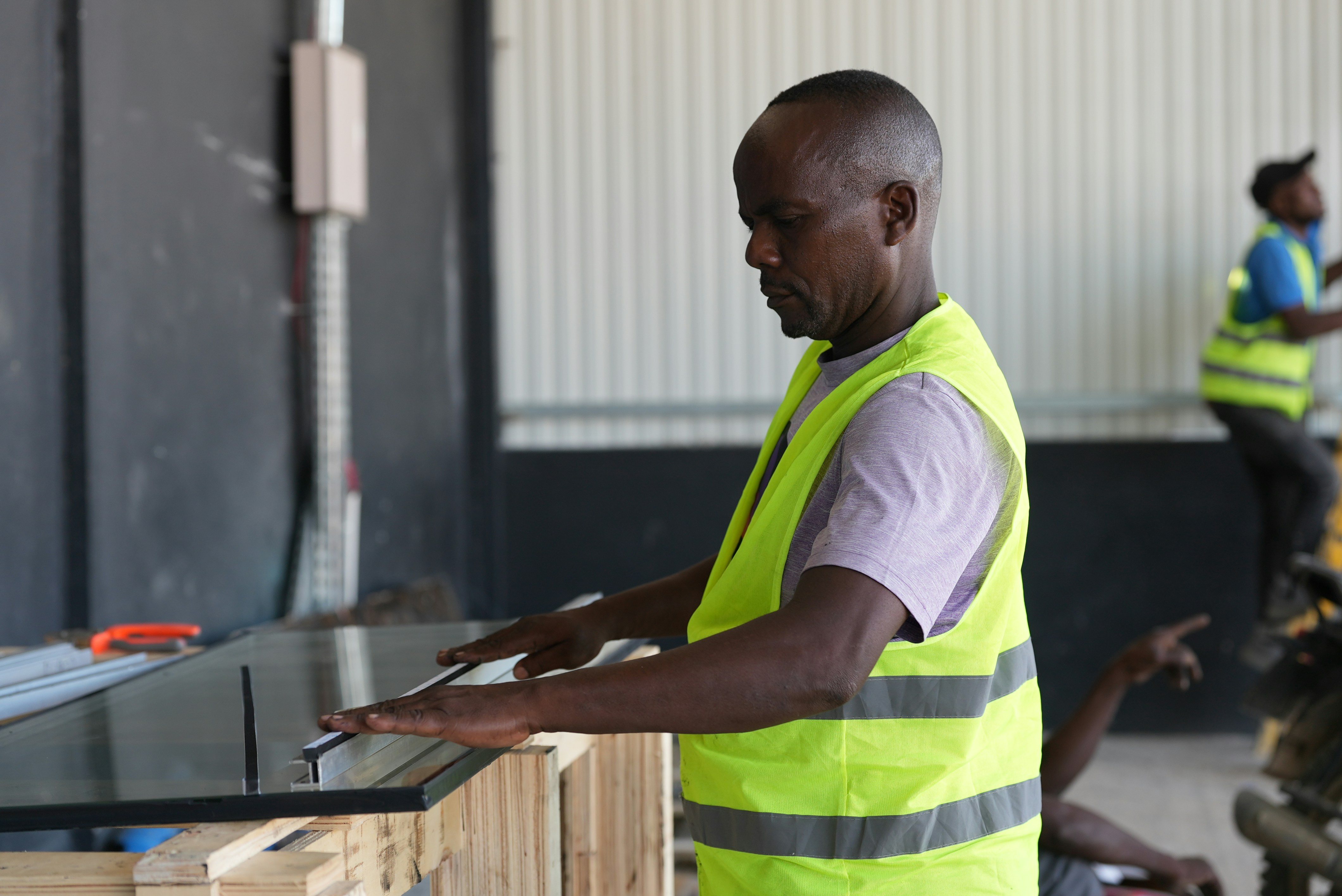 Worker in a high-visibility vest checking a panel in a workshop, the daily floor work that supervisor training Oshawa programs are built around