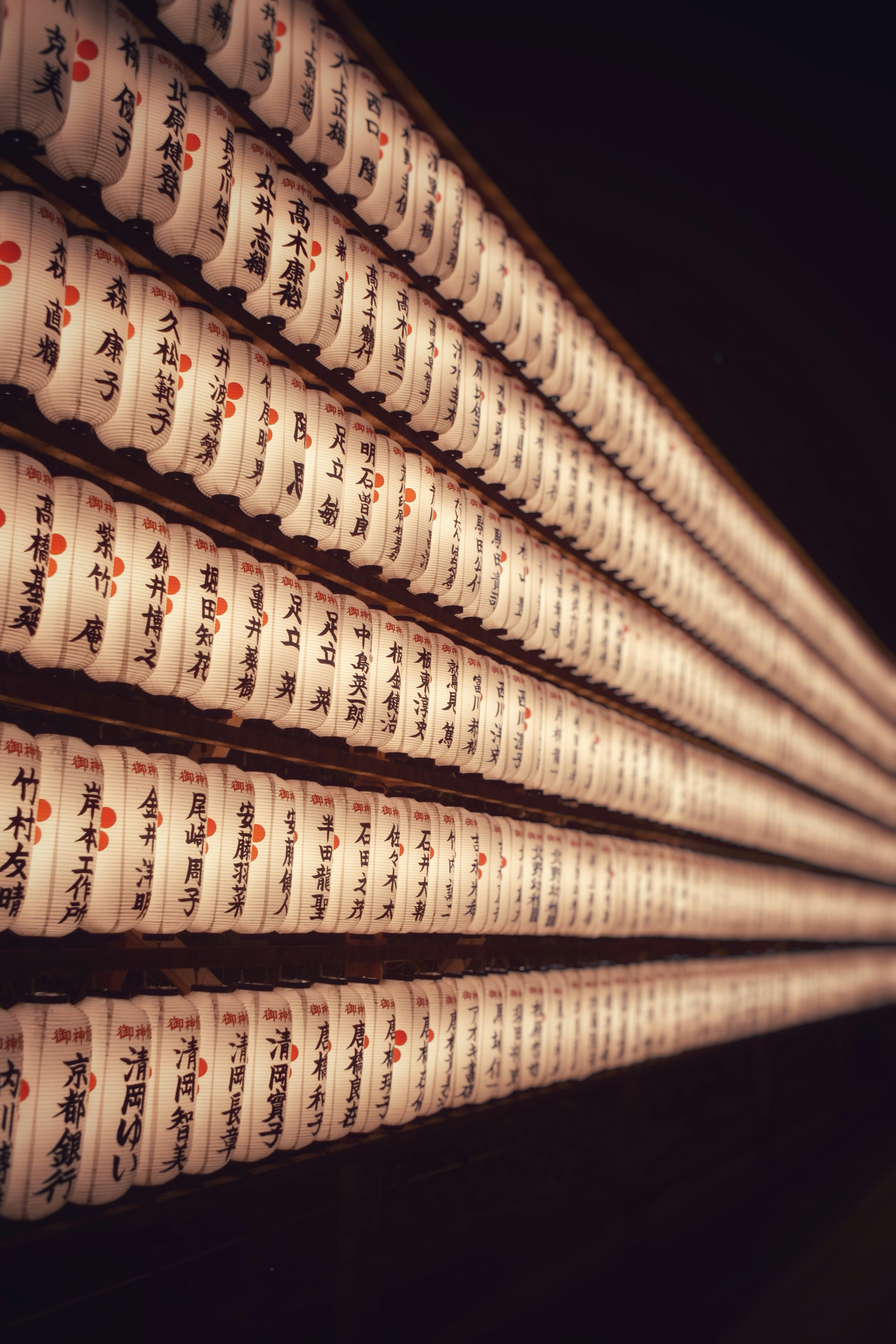 Rows of white paper lanterns with black Japanese calligraphy and red dots