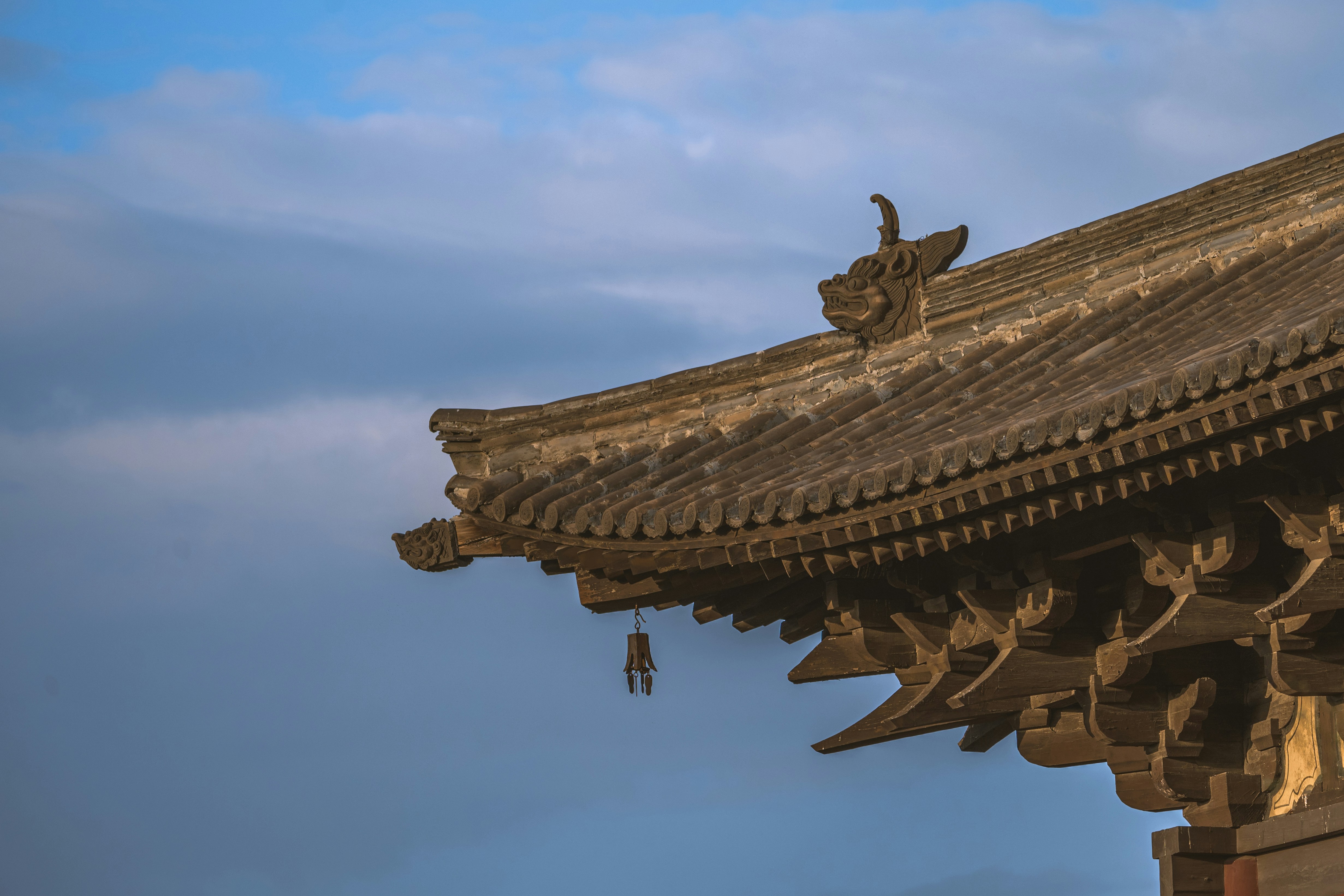 The curved tiled roof of a traditional building with a carved dragon ornament