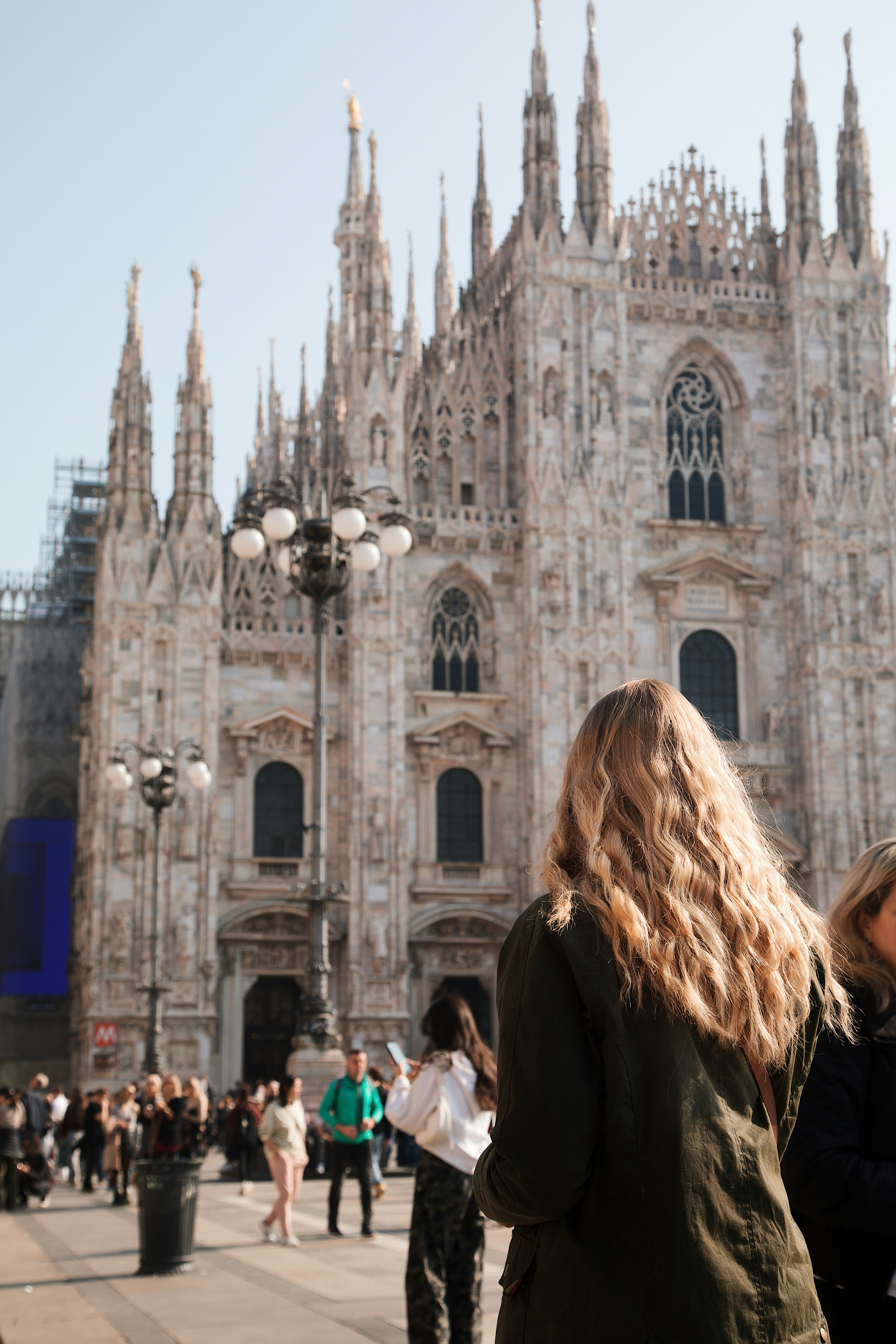 A person with long wavy hair facing the Duomo di Milano in Milan