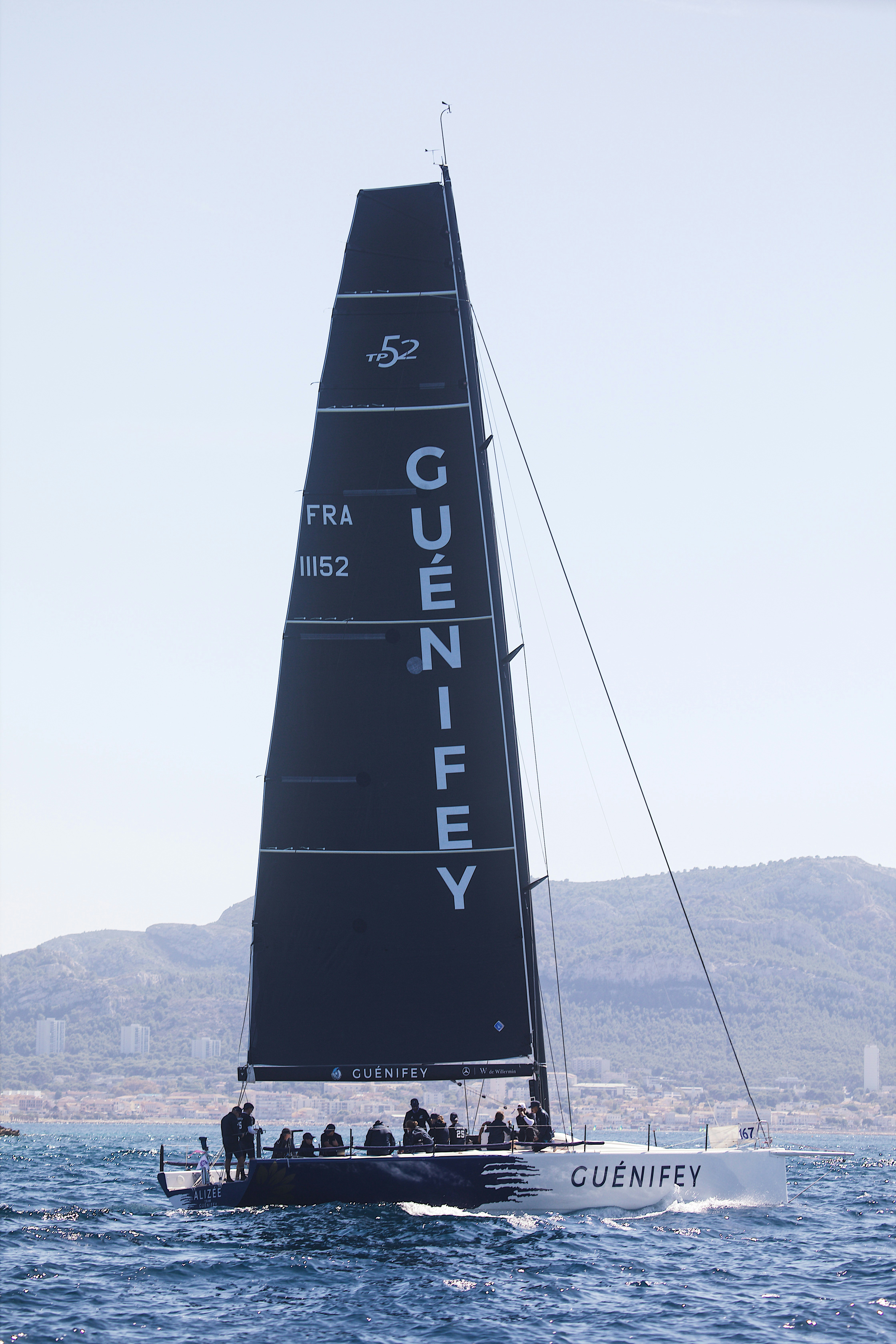 A TP52 racing sailboat with a black sail sailing on the sea