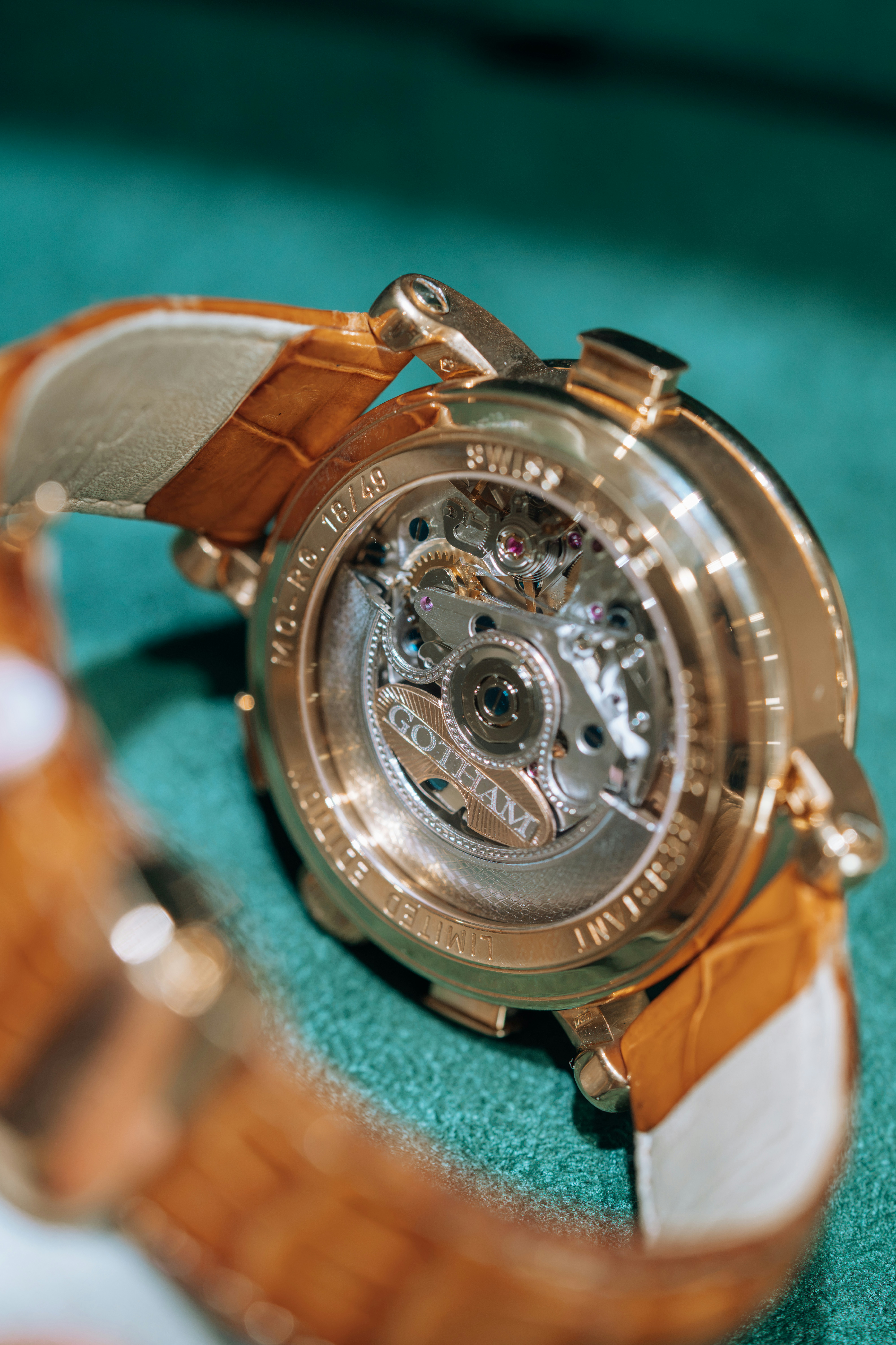 The back of a gold watch with a visible mechanical movement on green fabric