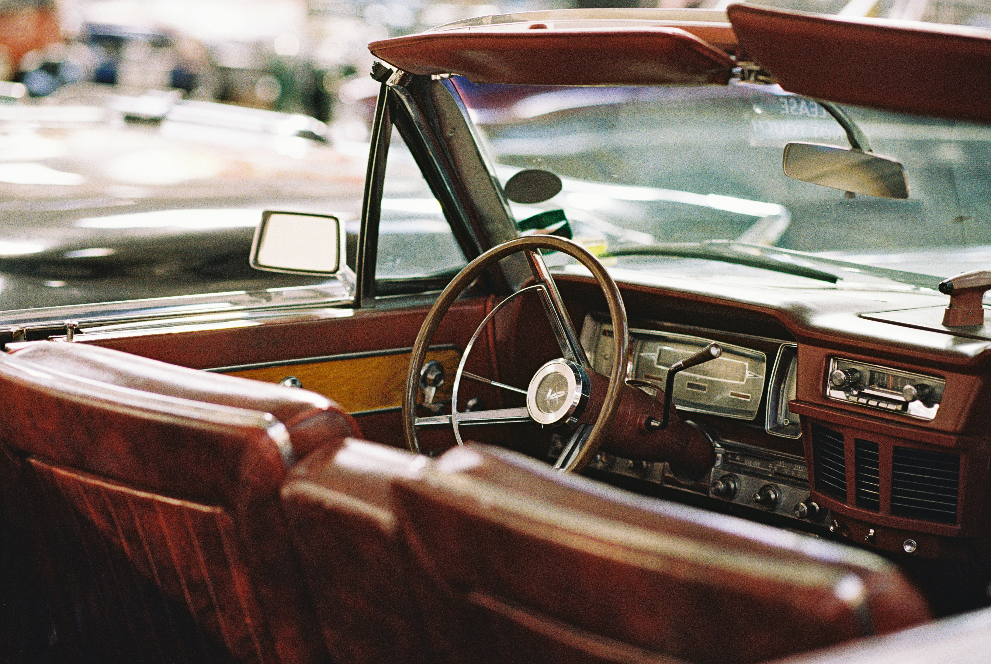The interior of a vintage convertible with brown leather seats and a steering wheel