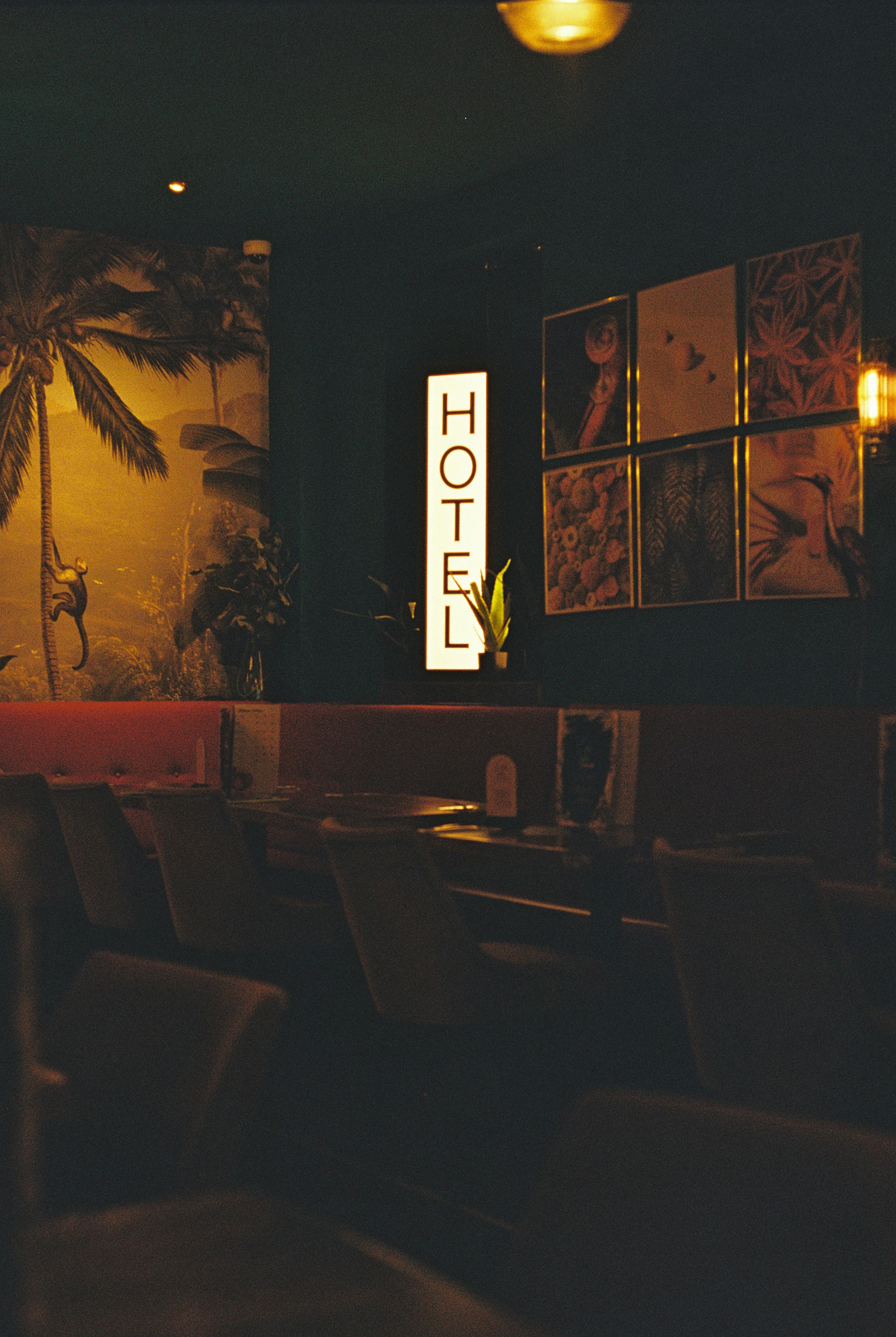A dimly lit lounge with a vertical sign reading HOTEL above a booth