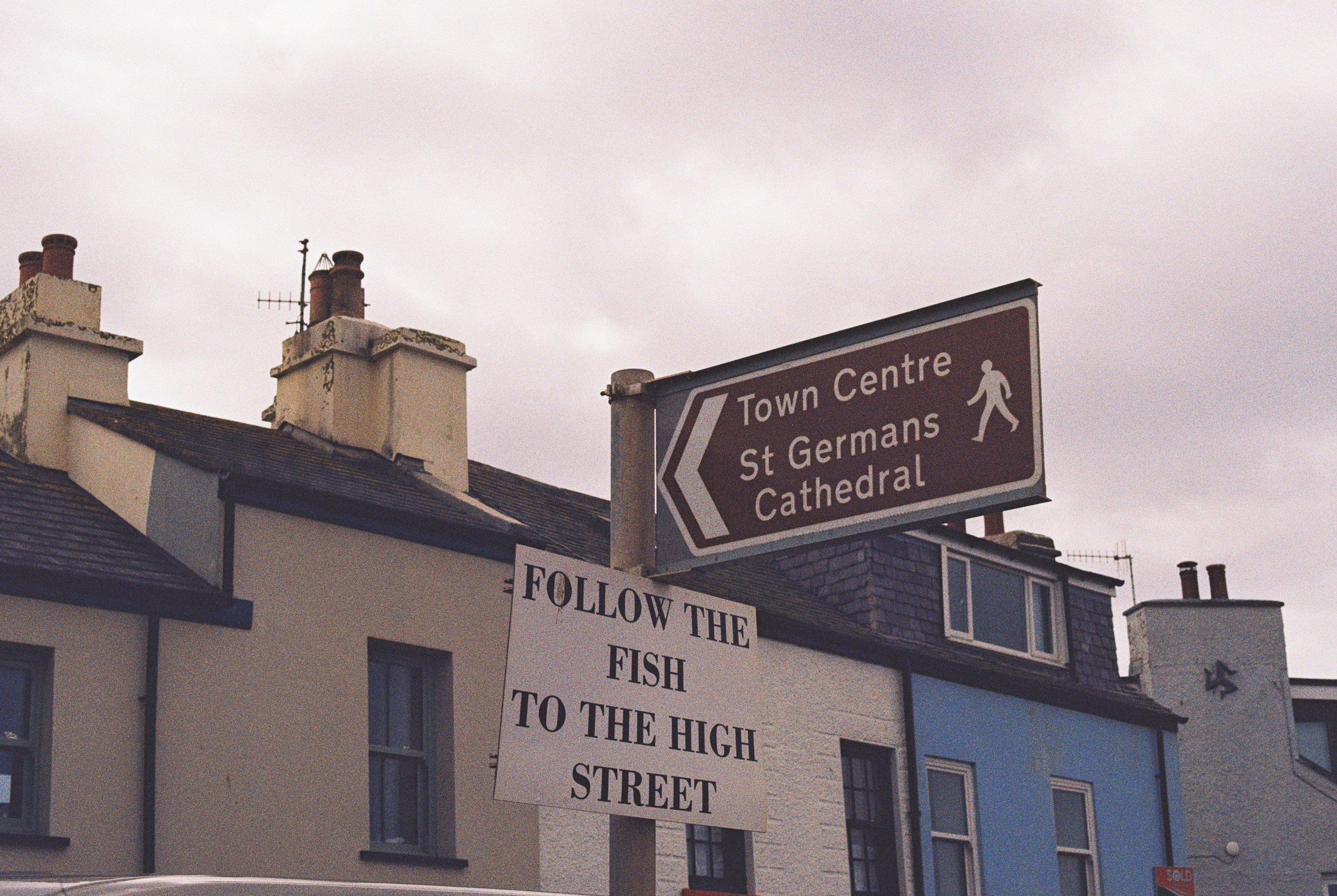 Street signs reading "Town Centre" and "FOLLOW THE FISH TO THE HIGH STREET" against buildings