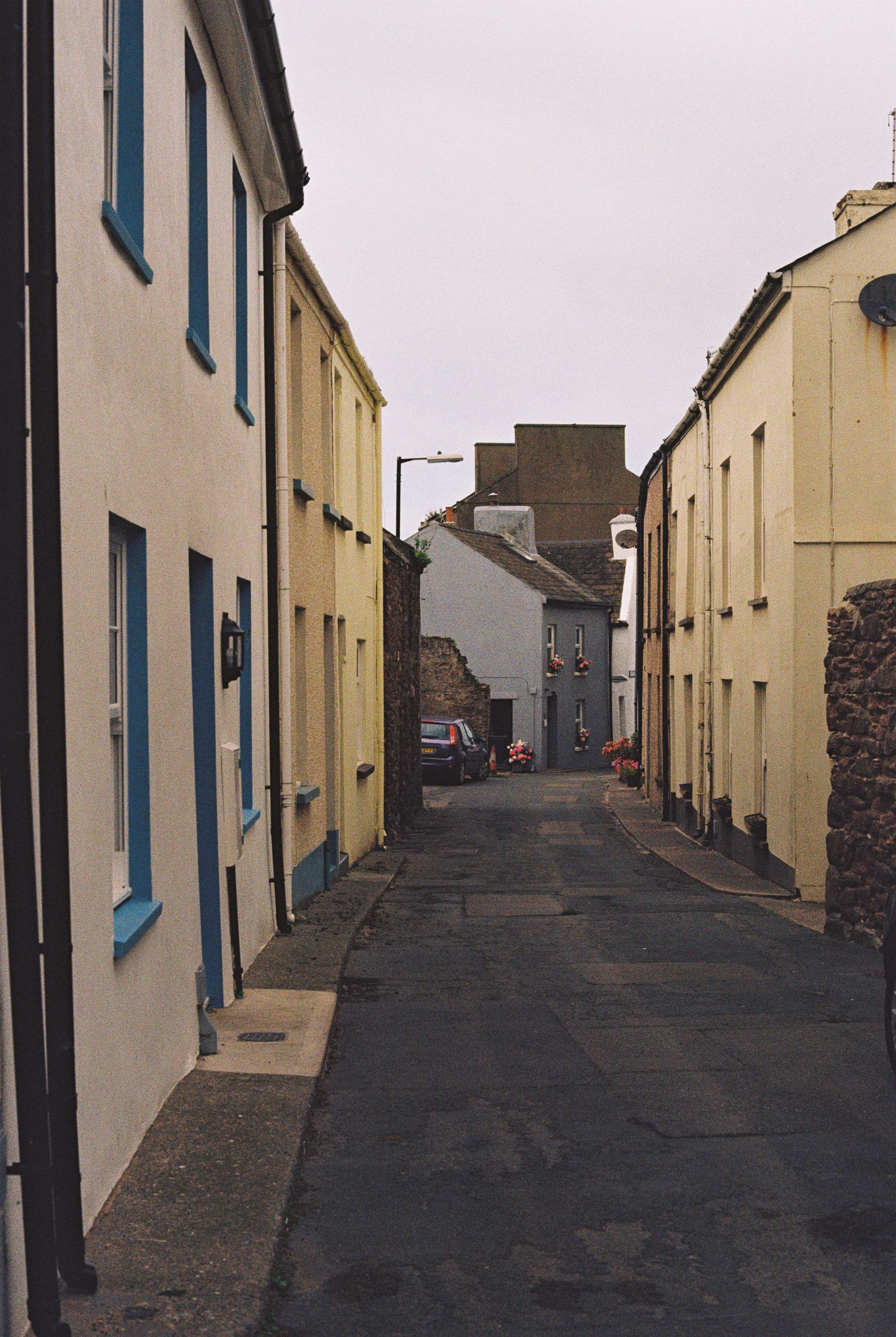 A narrow street lined with pastel colored houses under an overcast sky