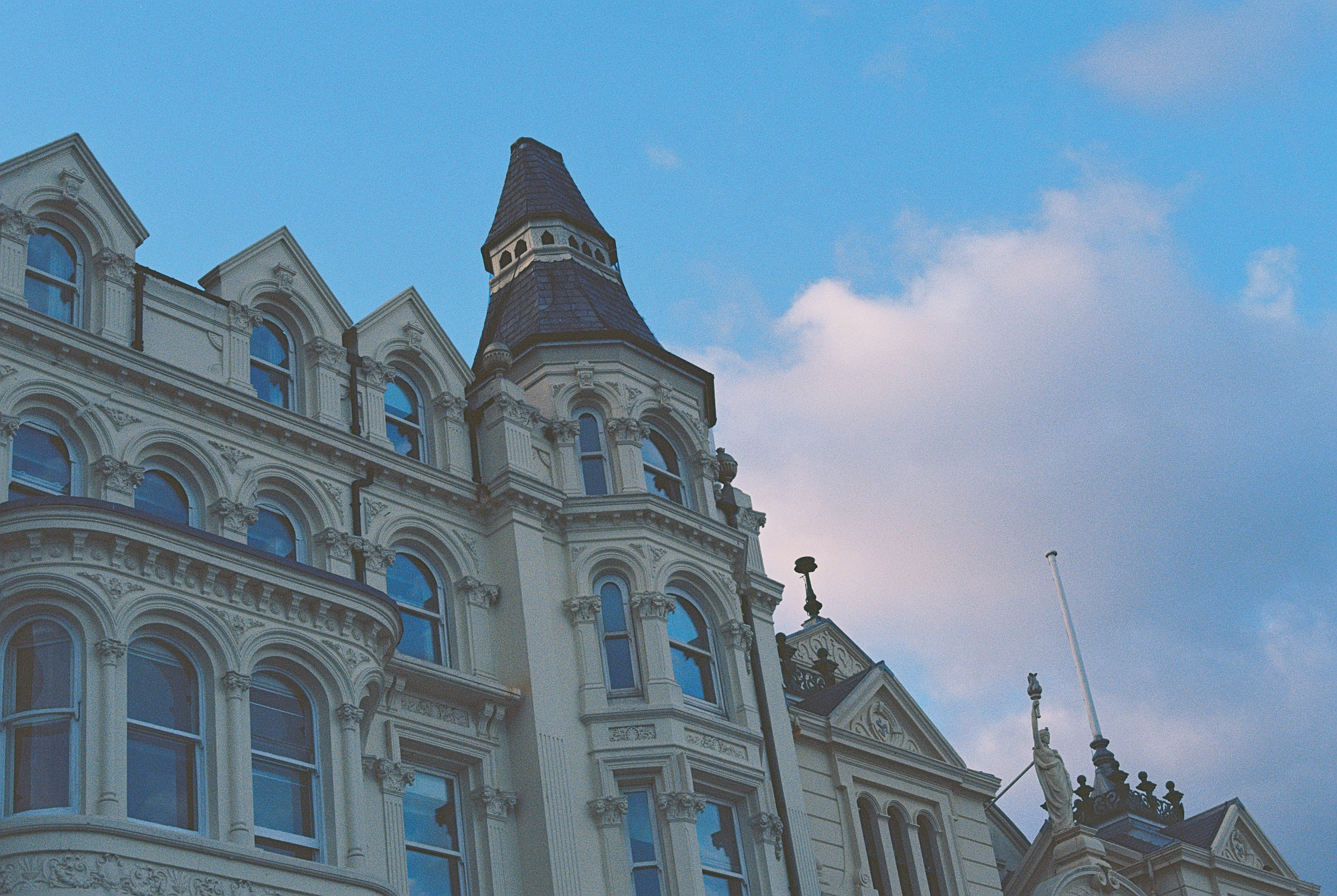 An ornate Victorian building with arched windows and a tower against a blue sky