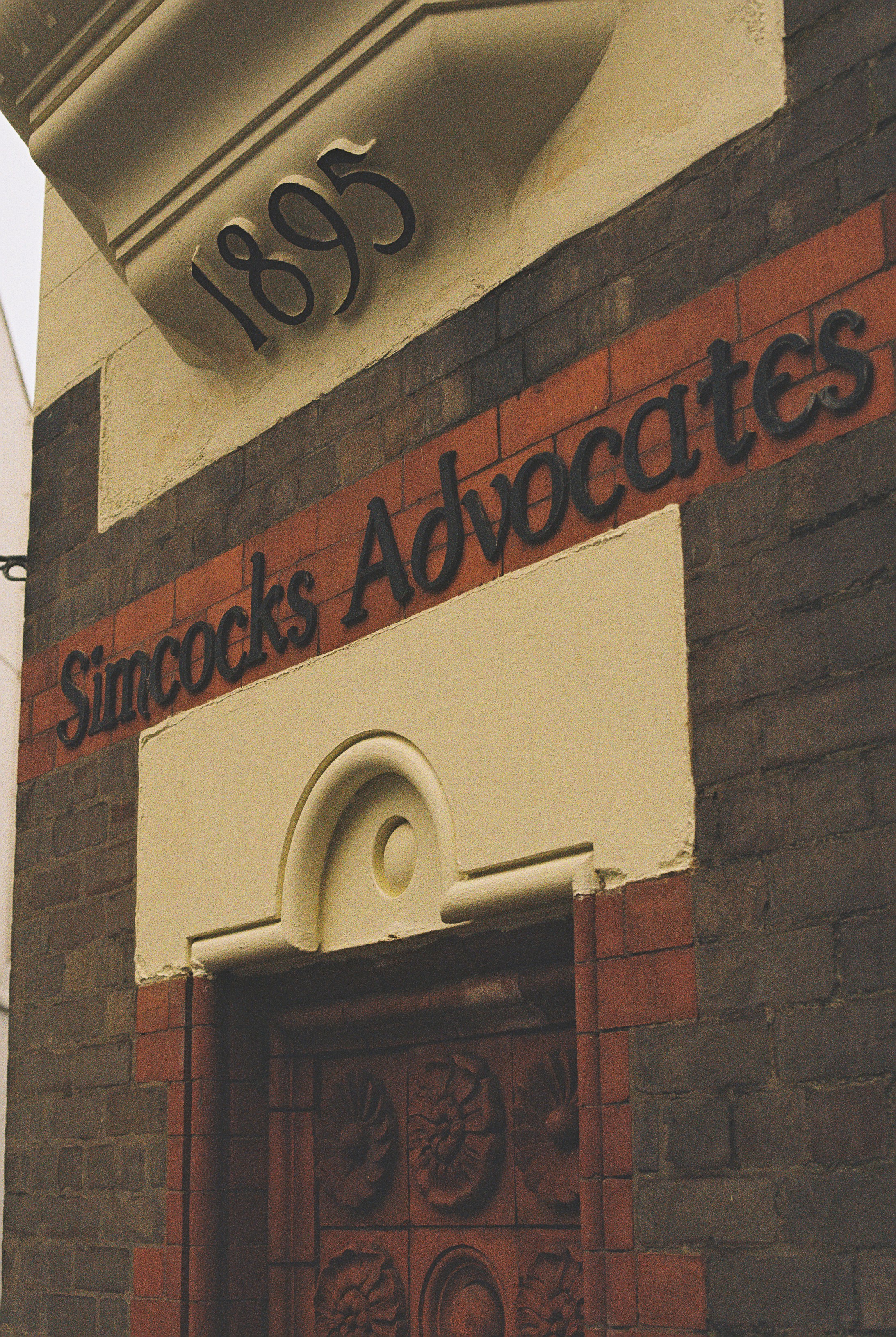 A brick building facade with the text Simcocks Advocates and the year 1895
