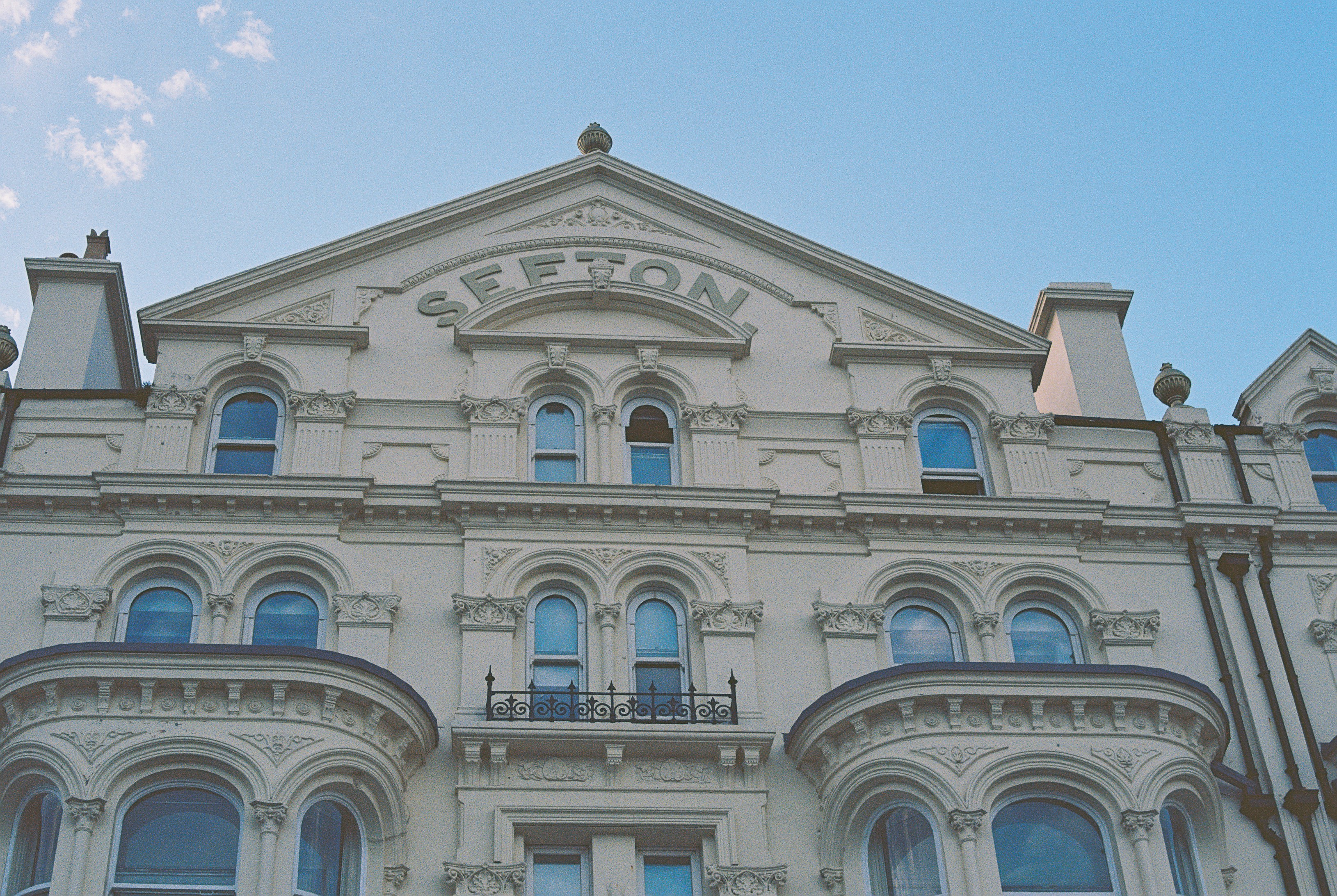 The ornate white facade of the Sefton building against a clear blue sky