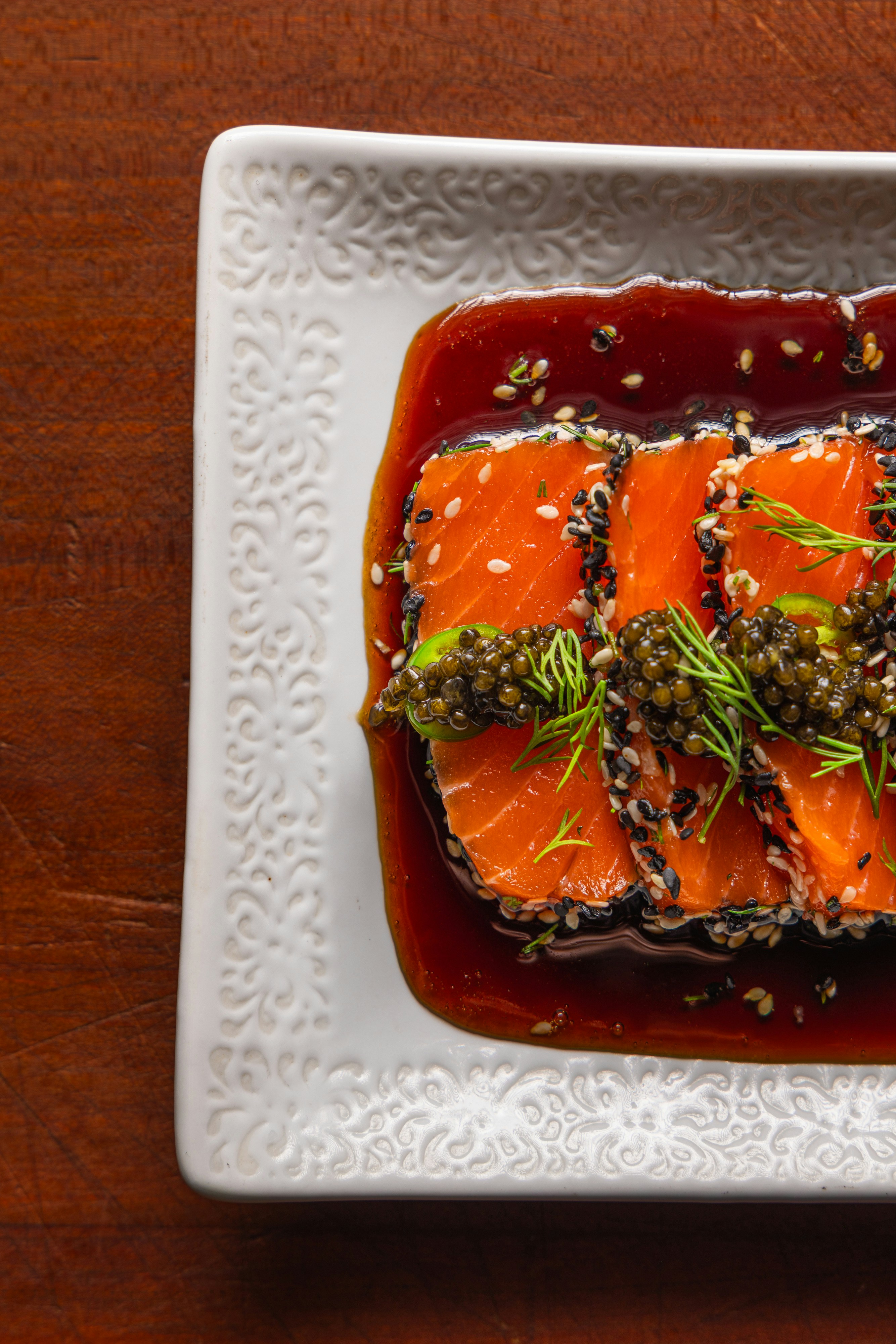 Slices of salmon with sesame seeds, caviar, and dill in soy sauce