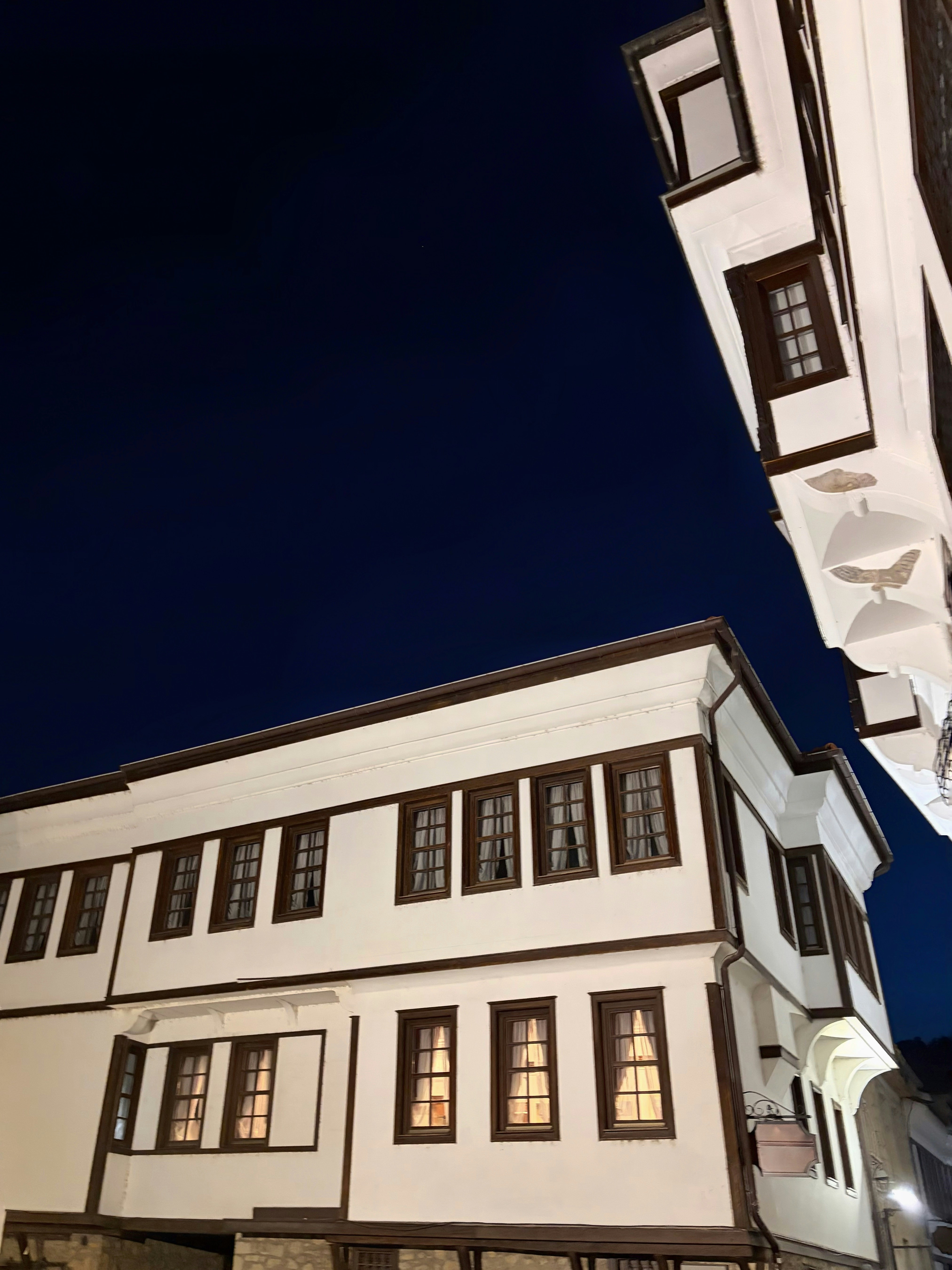 Traditional white houses with dark wooden trim against a deep blue night sky